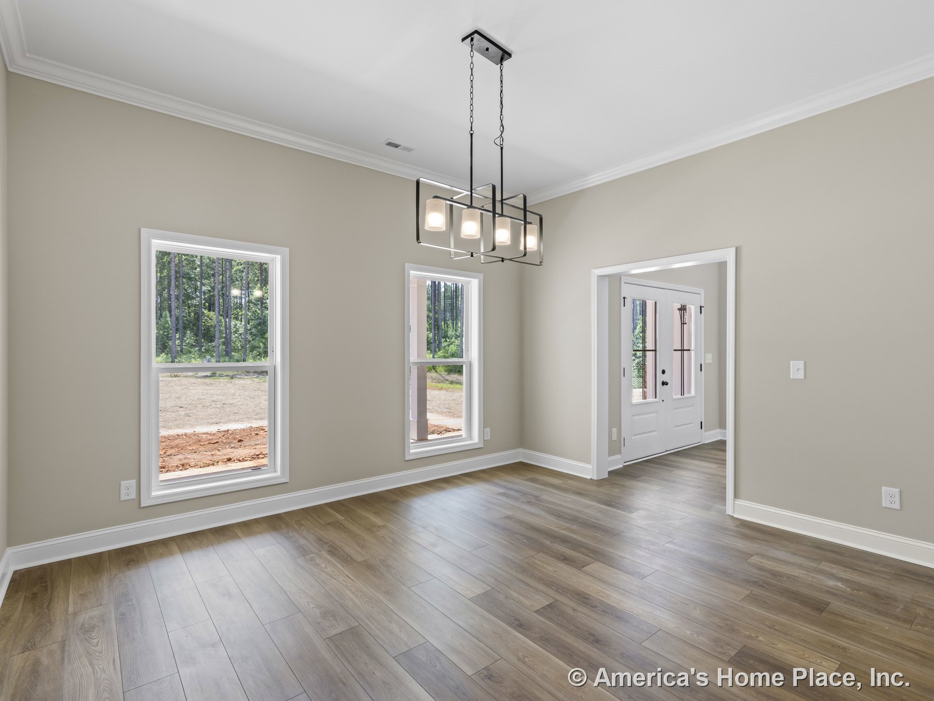 Dining area with wood-look plank flooring, two large windows framed in white trim, modern rectangular chandelier, neutral walls, crown molding ceiling, and adjacent entryway