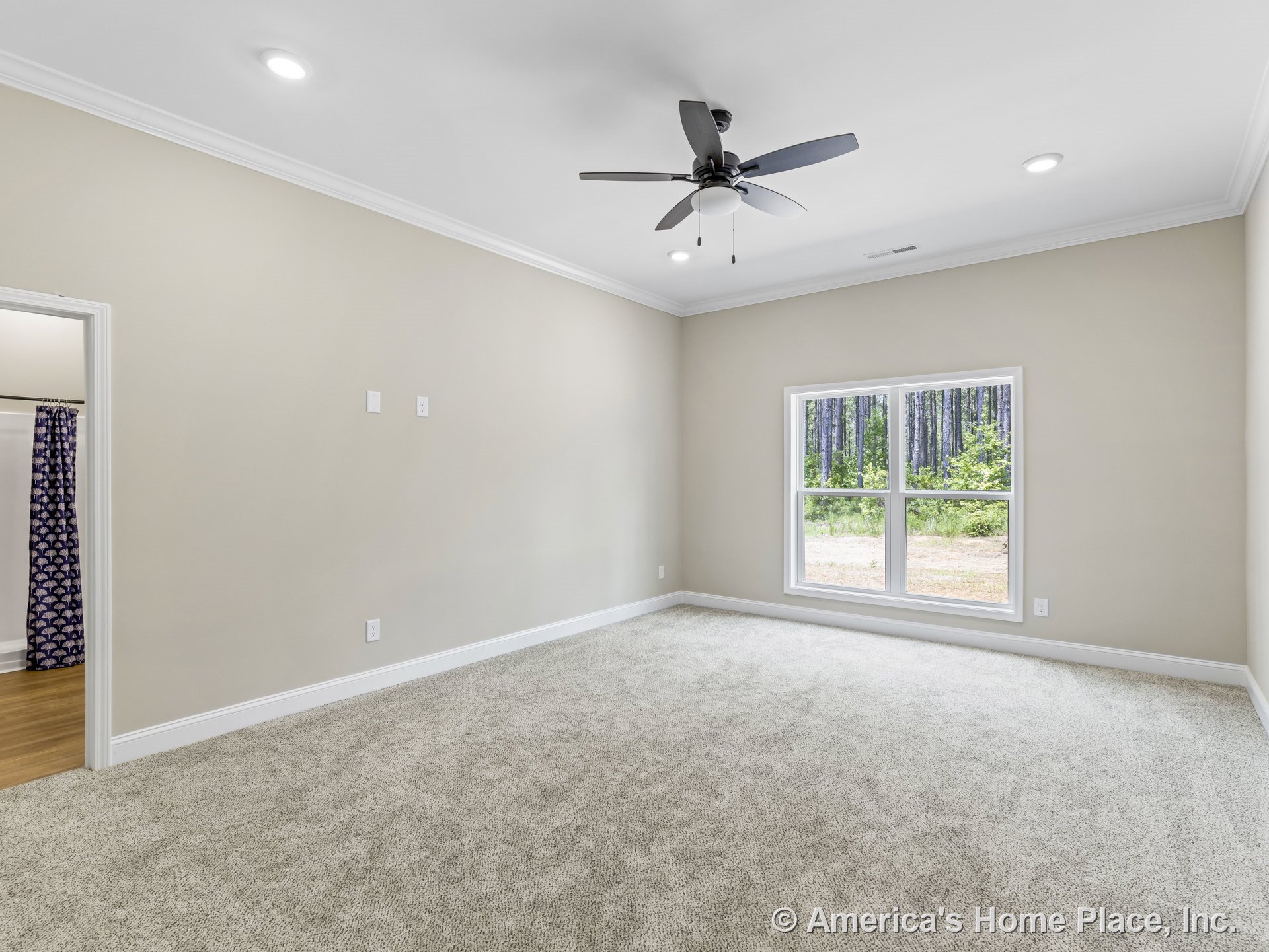 Carpeted bedroom with neutral walls, white trim and baseboards, large double window allowing natural light, ceiling fan with integrated light, recessed ceiling lights, crown