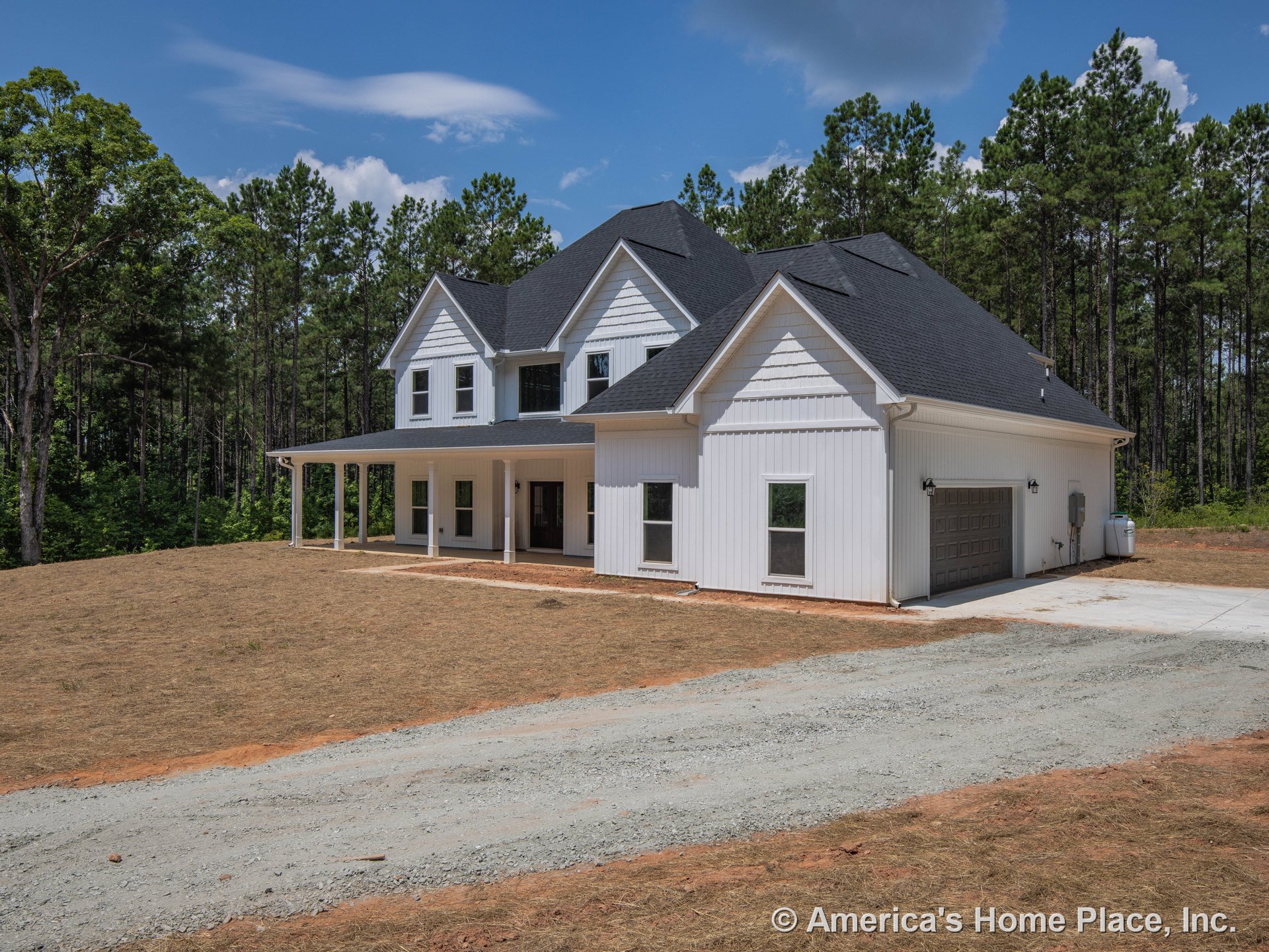 White board and batten siding with black shingle roof, covered front porch supported by columns, attached two-car garage, multiple double-hung windows, concrete driveway, built-in