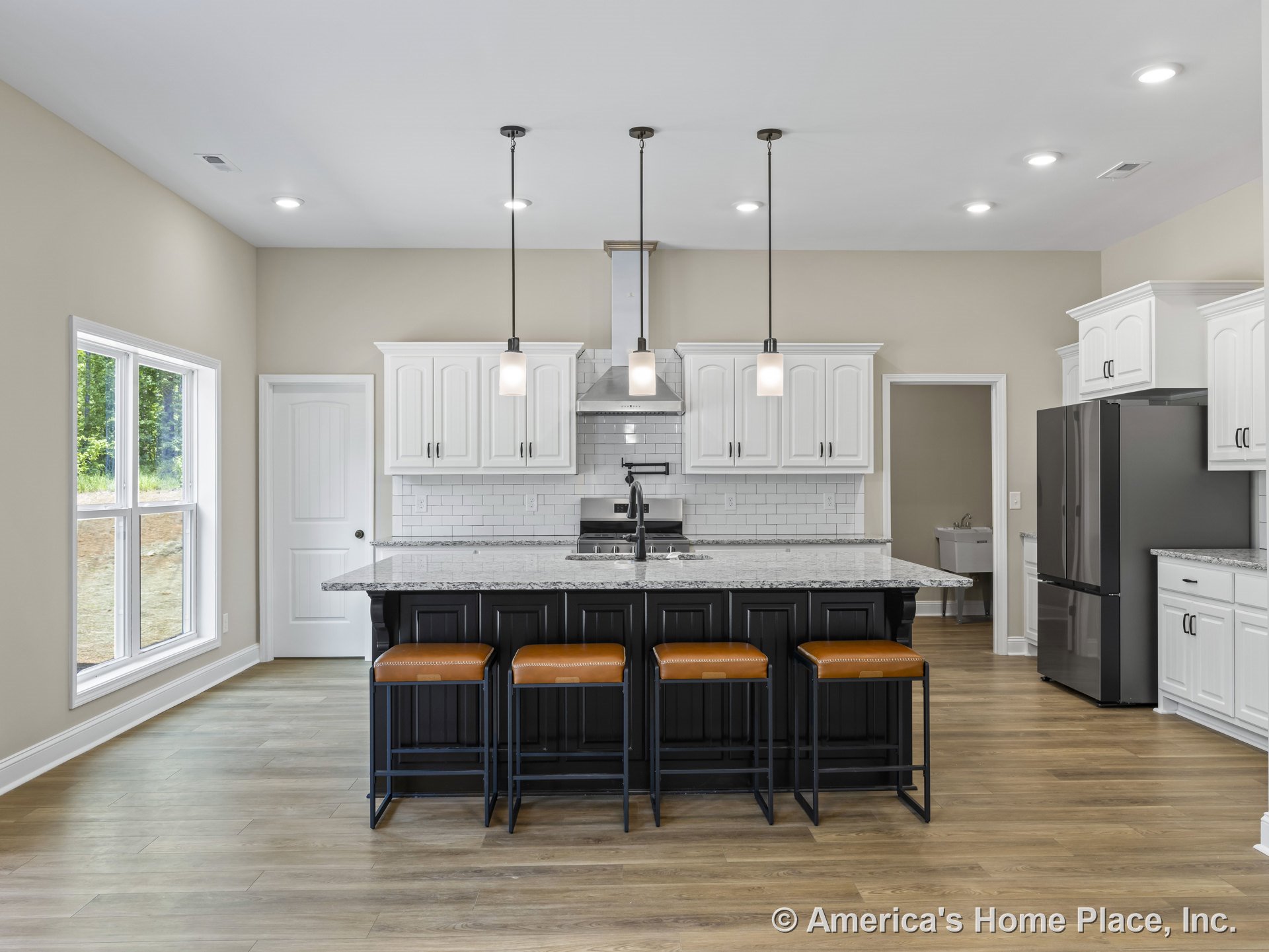 White shaker cabinetry and a large black island with granite countertops, subway tile backsplash, pendant lighting above the island, stainless steel appliances, double window with