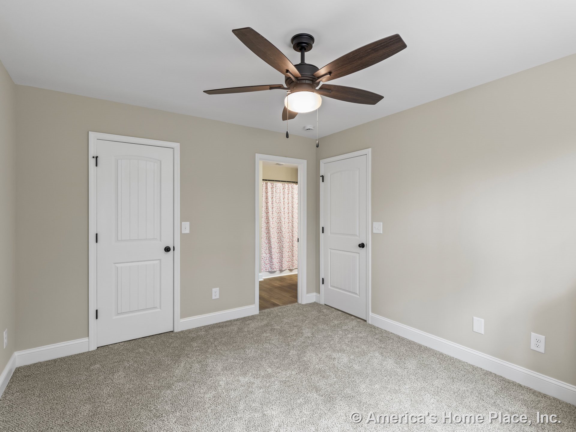 Bedroom with beige walls, white baseboards and trim, carpet flooring, paneled white doors, ceiling fan with built-in light, and closet doors.