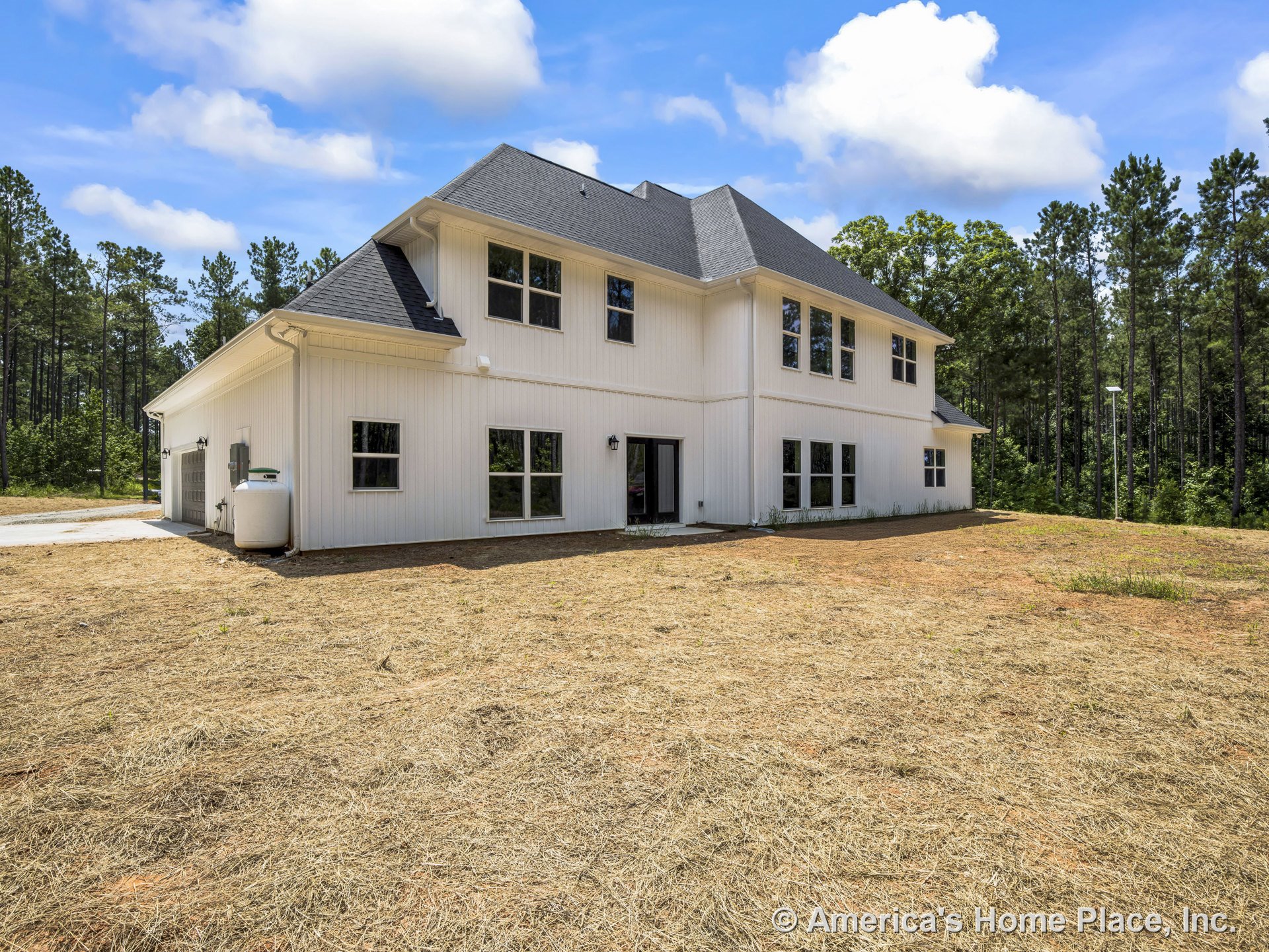 White vertical siding and dark shingle roof on a two-story modern farmhouse with multiple large windows, attached garage, double entry doors, outdoor utility tank, decorative trim