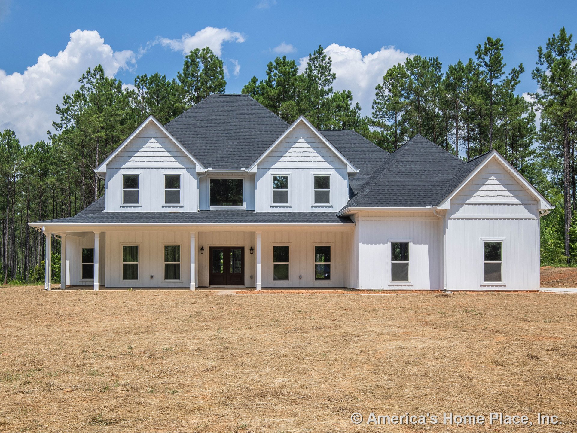 White board and batten siding with covered front porch, black shingle roof featuring multiple gables, double front doors, and symmetrical window placement.
