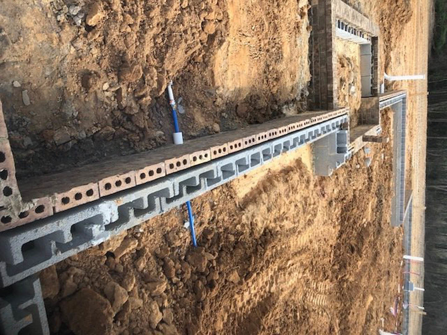 Concrete block wall under construction at residential site with exposed masonry and gravel ground