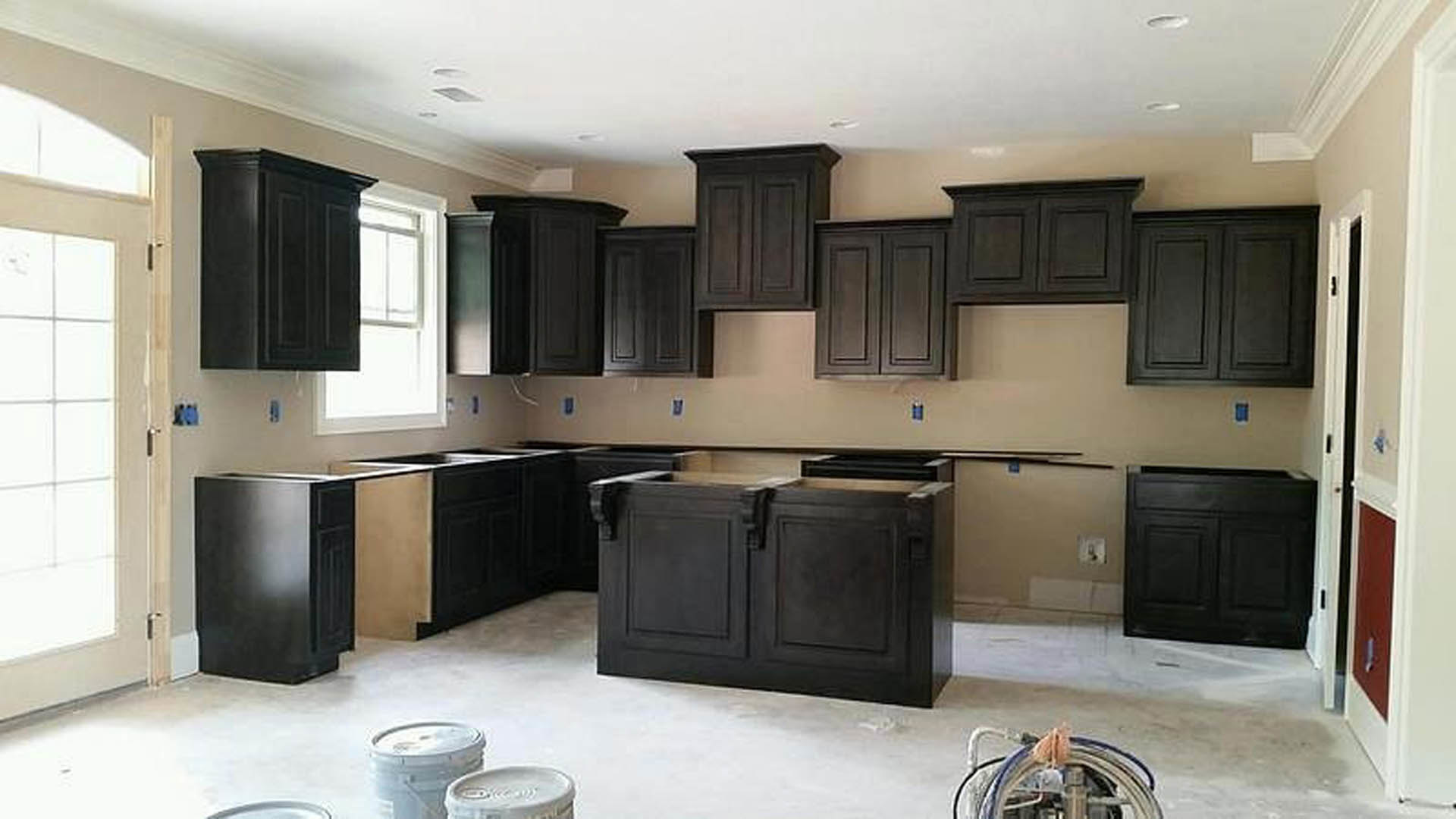 Kitchen with matte black cabinets, white quartz countertops, stainless steel appliances, and a deep undermount sink beneath a tiled backsplash.