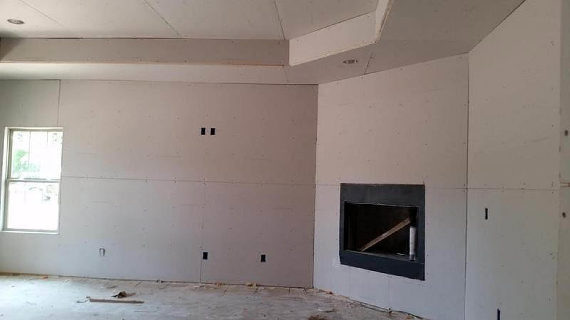 Modern living room with plaster walls, black-framed fireplace, white-trimmed window, and polished concrete floor