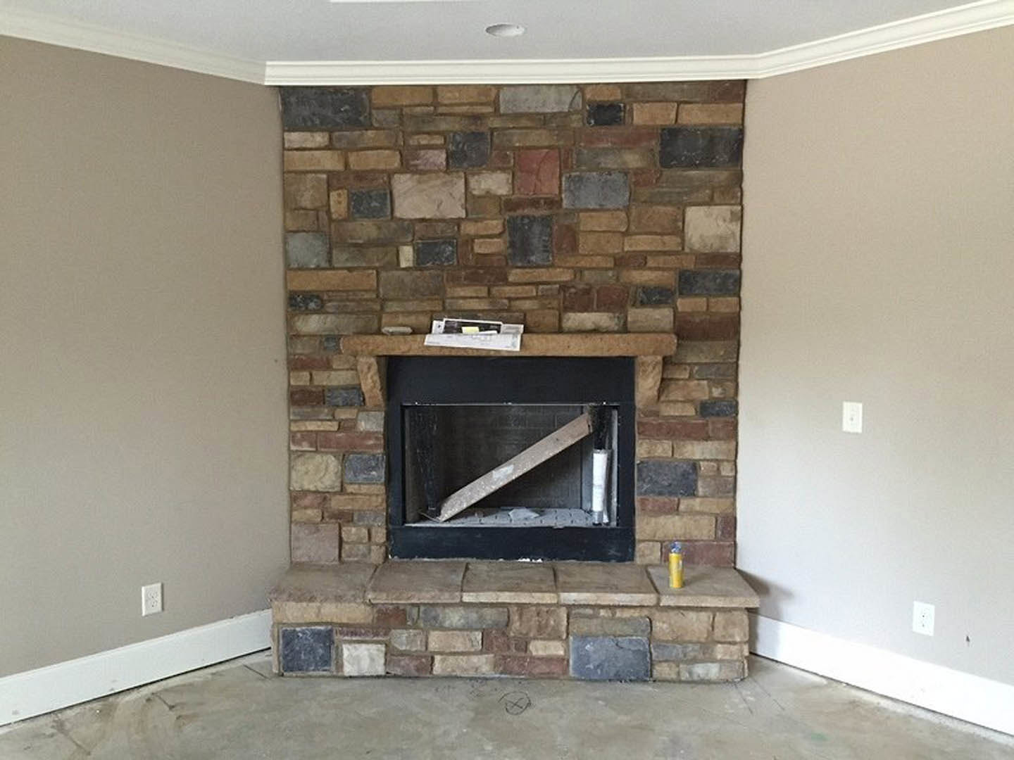 Brick fireplace with wood beam mantel, plaster walls, and wood burning stove in a cozy living room.