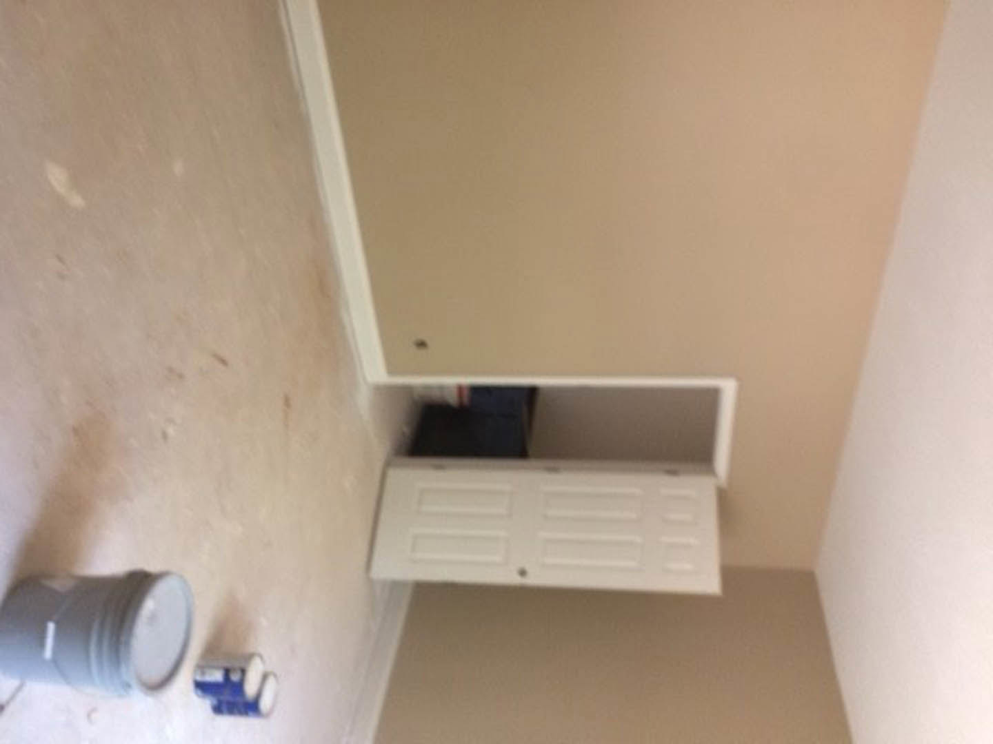 Open white door in a bathroom with plaster walls, can of paint on light-colored floor