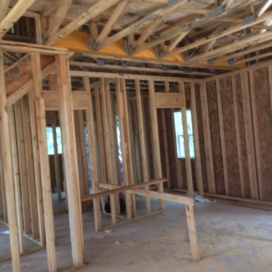 Dining area with exposed wood ceiling beams, hardwood table, and large window letting in natural light