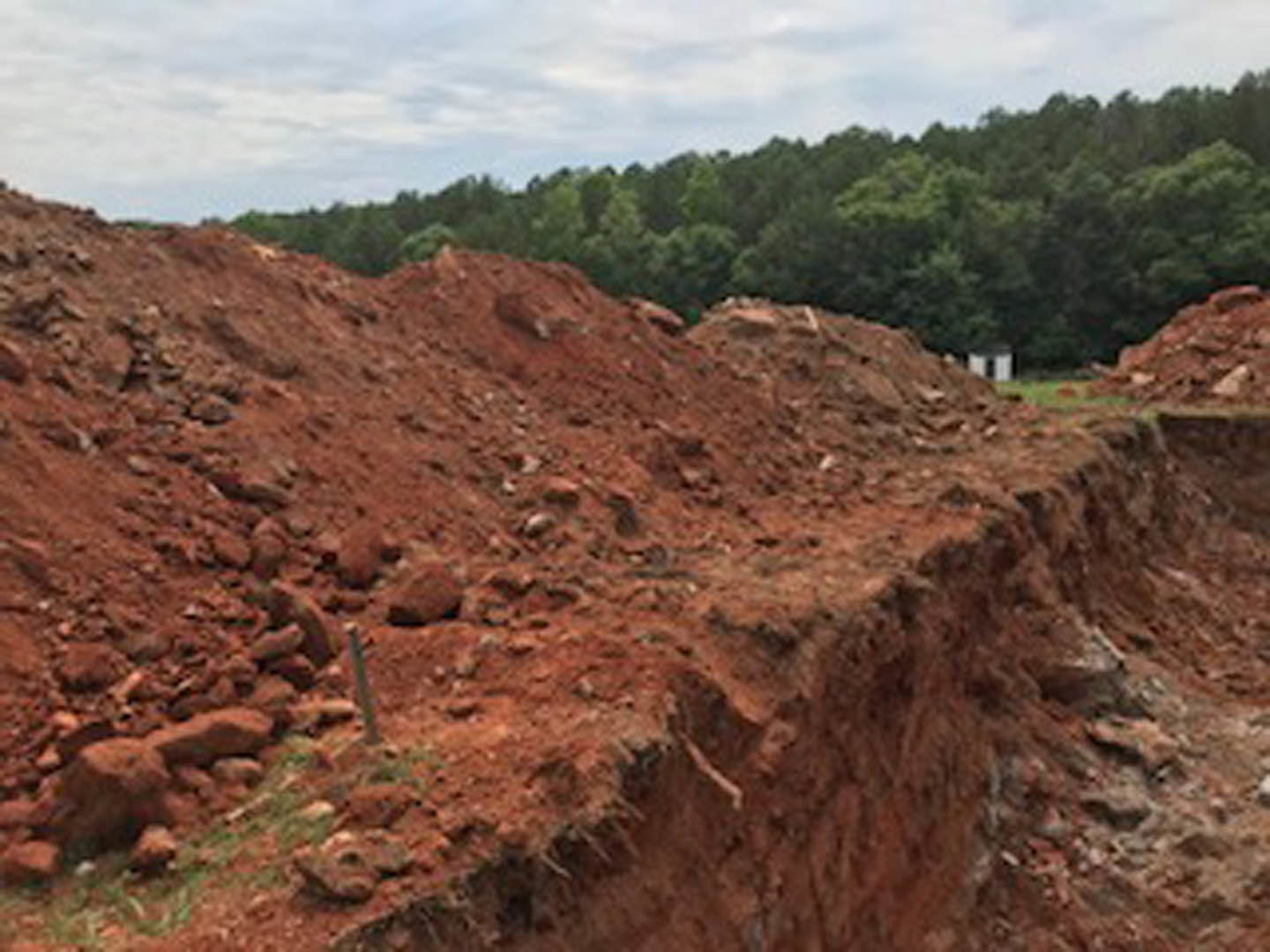 Dirt hill with scattered trees in the background under a cloudy sky