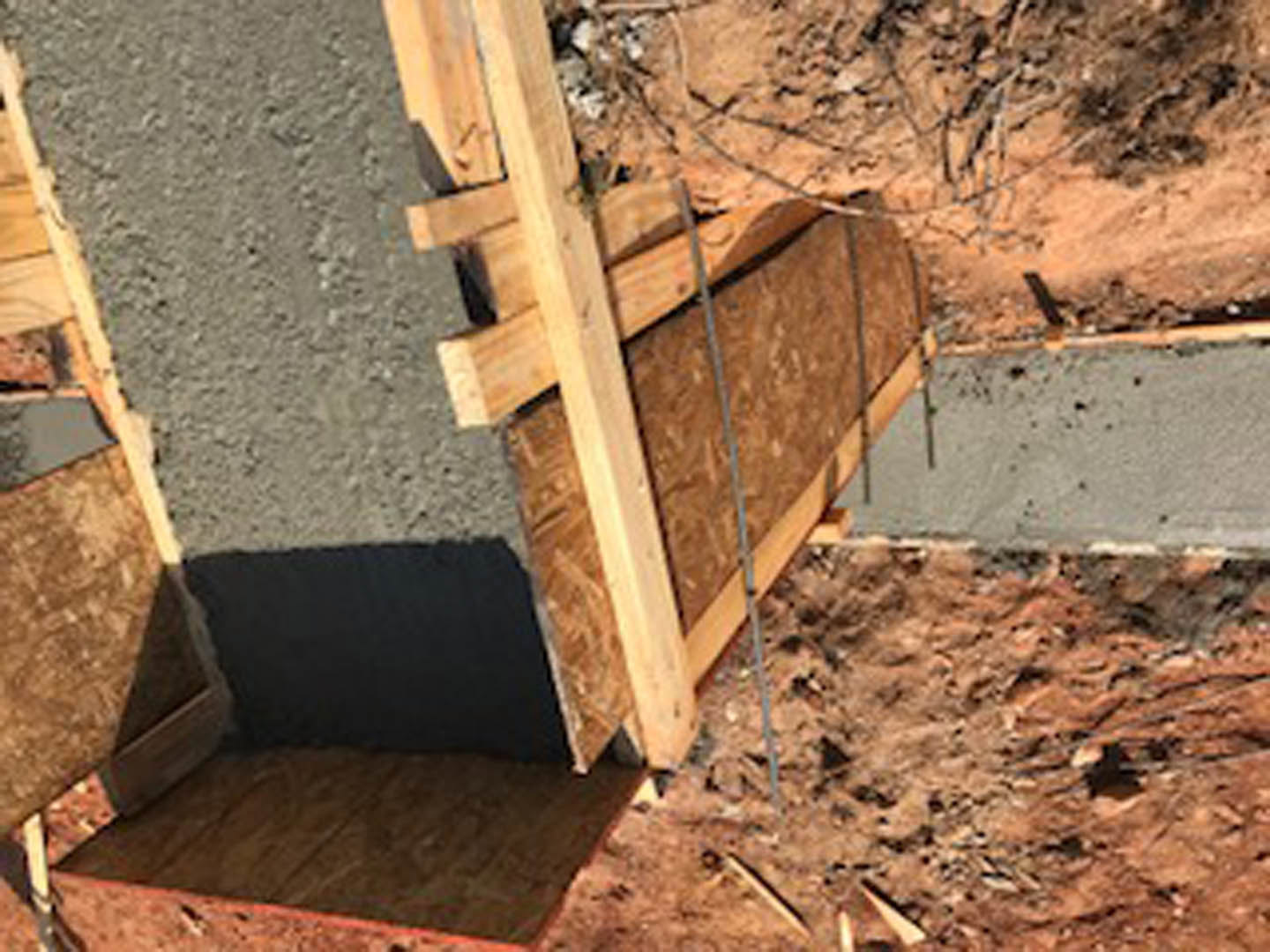 Wood framing structure with exposed lumber beams and cement slab foundation at a residential construction site