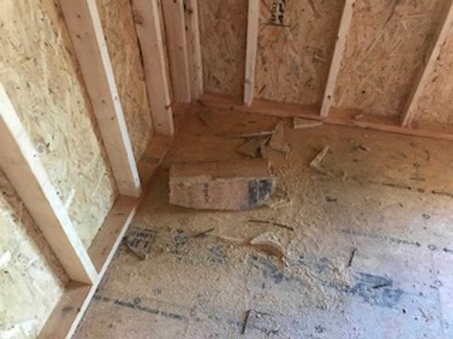Wood-paneled walls with exposed brick section, unfinished lumber beams, and construction debris scattered on floor