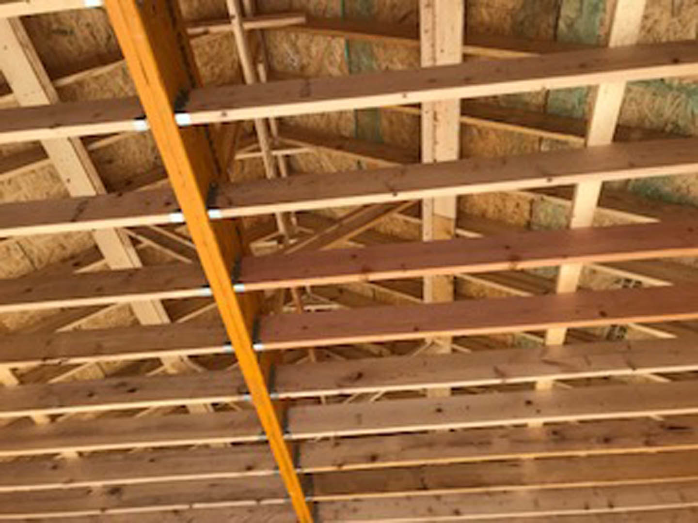 Exposed wooden beams and planks forming a roof frame with visible insulation
