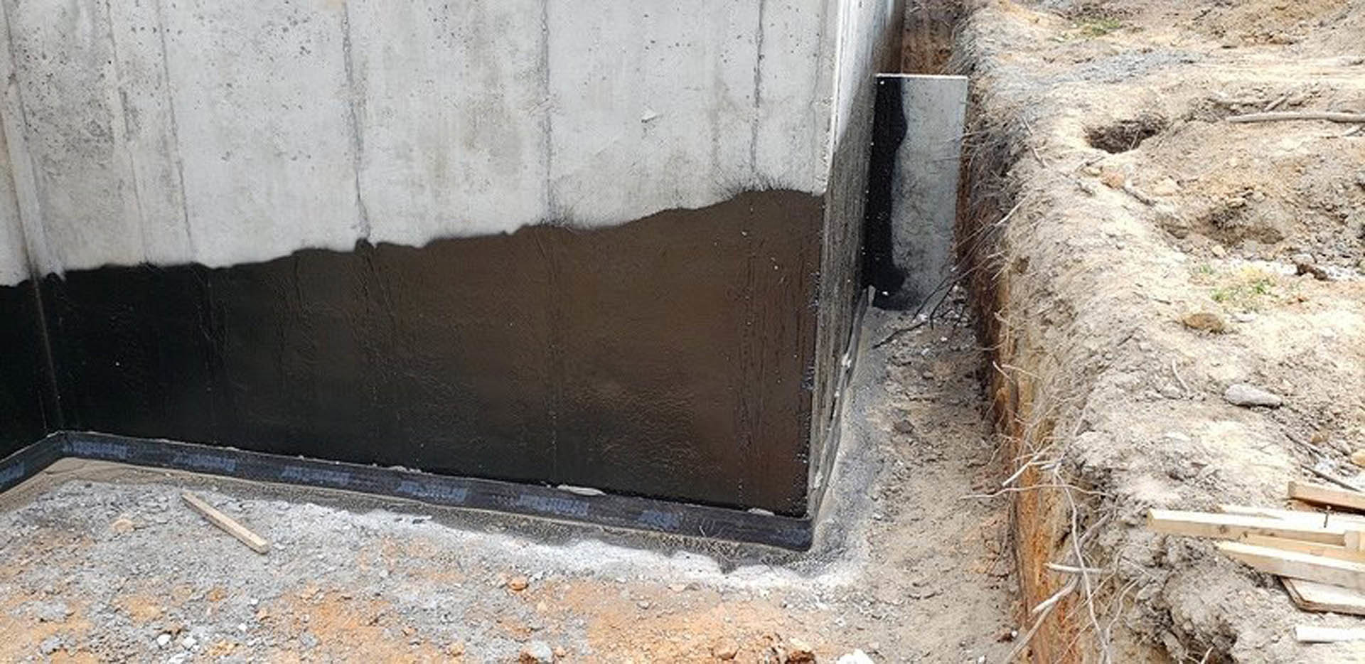Concrete foundation surrounded by exposed dirt, adjacent to contrasting black and white exterior walls