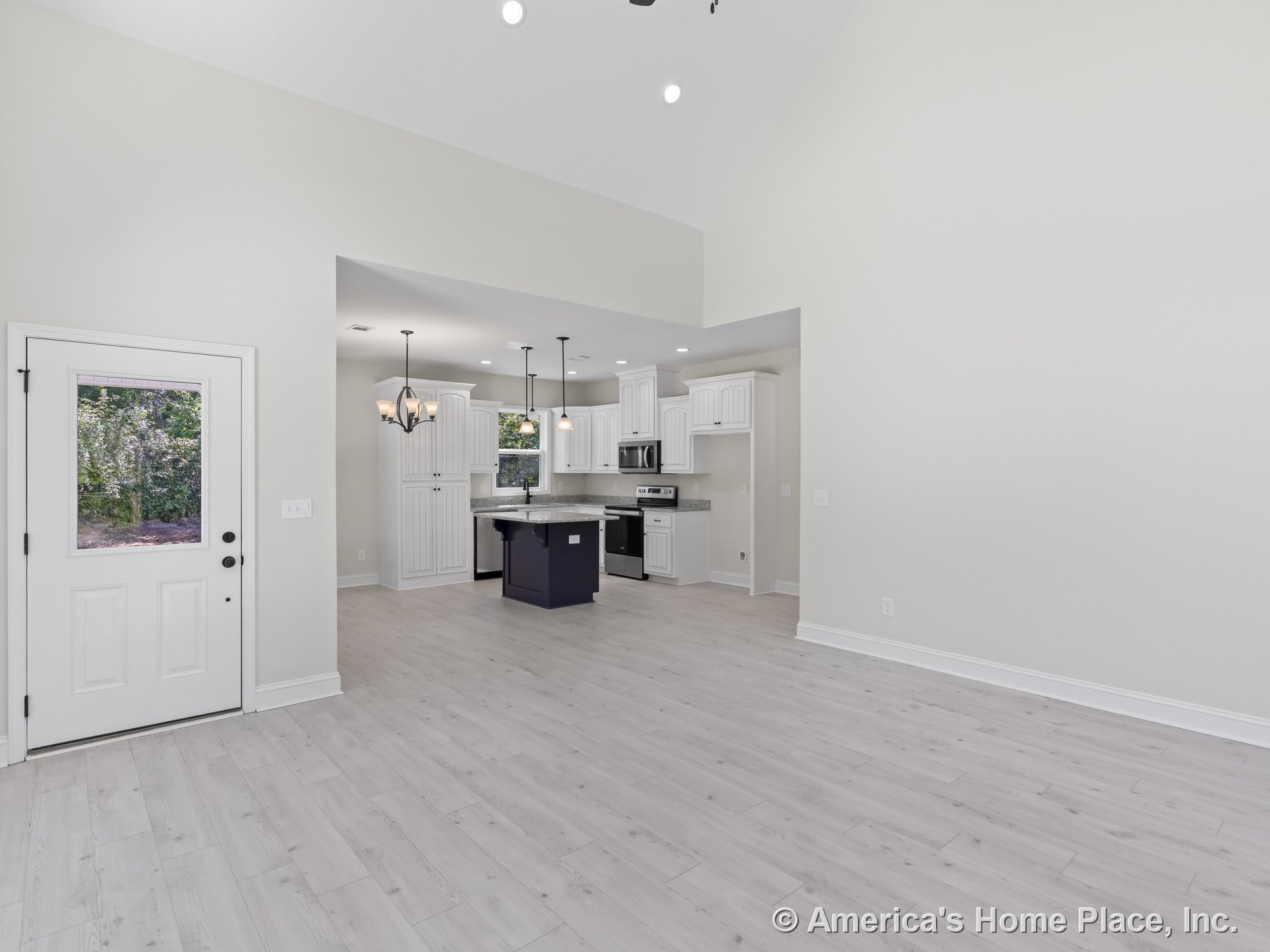 Open-concept kitchen with vaulted ceiling, light wood flooring, white shaker cabinets, granite countertops, stainless steel appliances, central island, multiple pendant lights, and