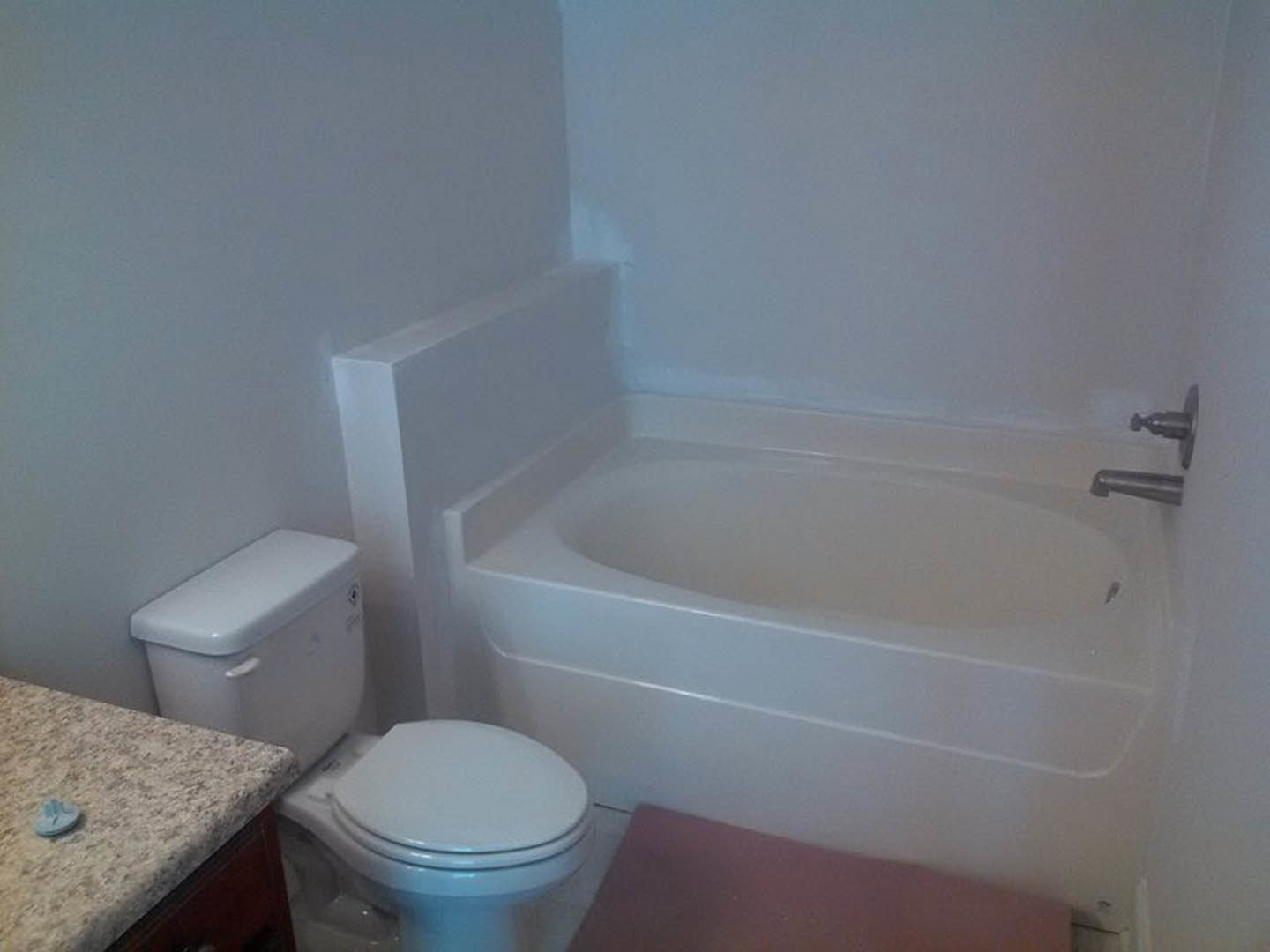 Bathroom with white bathtub, toilet, and sink; tiled walls and floor; blue soap dispenser on countertop; chrome faucet fixtures