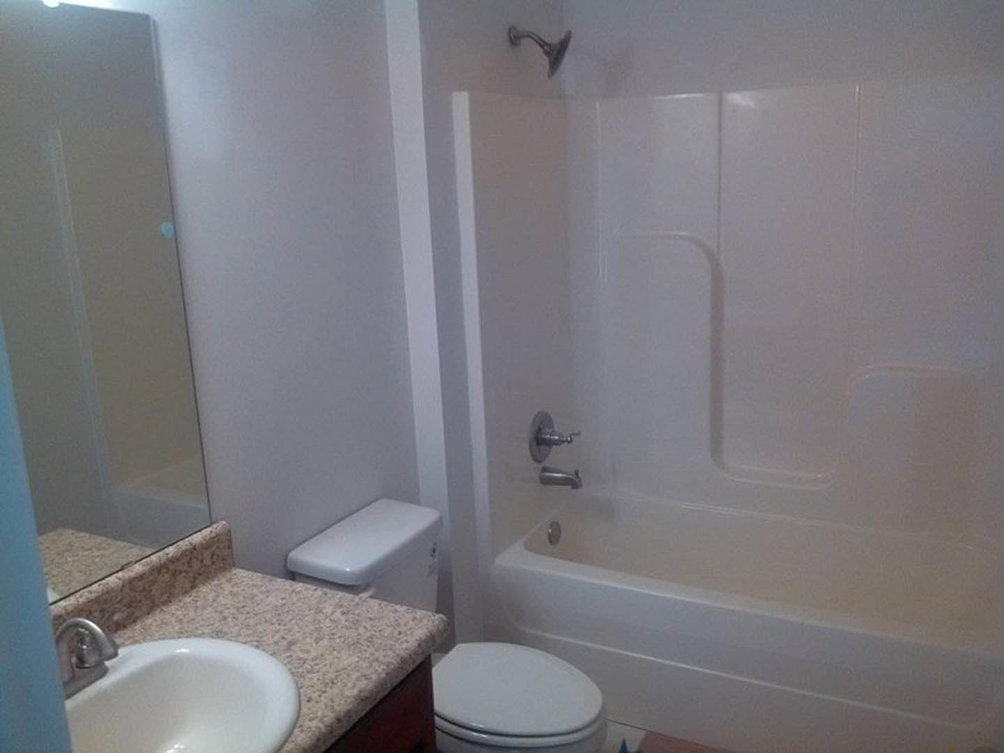 Modern bathroom with white ceramic sink, wall-mounted toilet, glass-enclosed shower, and light gray tile walls