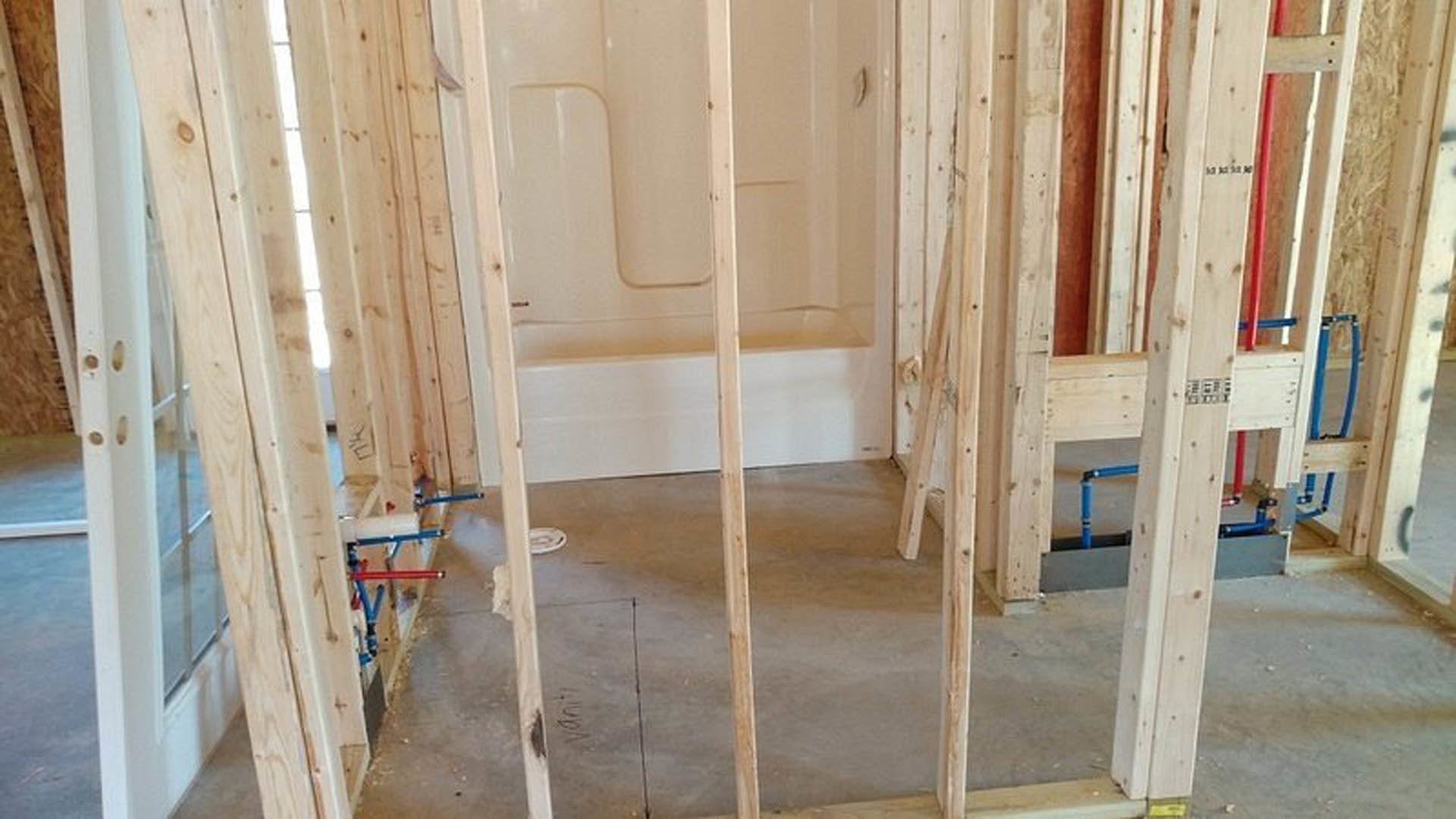 Bathroom featuring freestanding soaking tub, glass-enclosed shower with wood trim, plaster walls, and light wood flooring