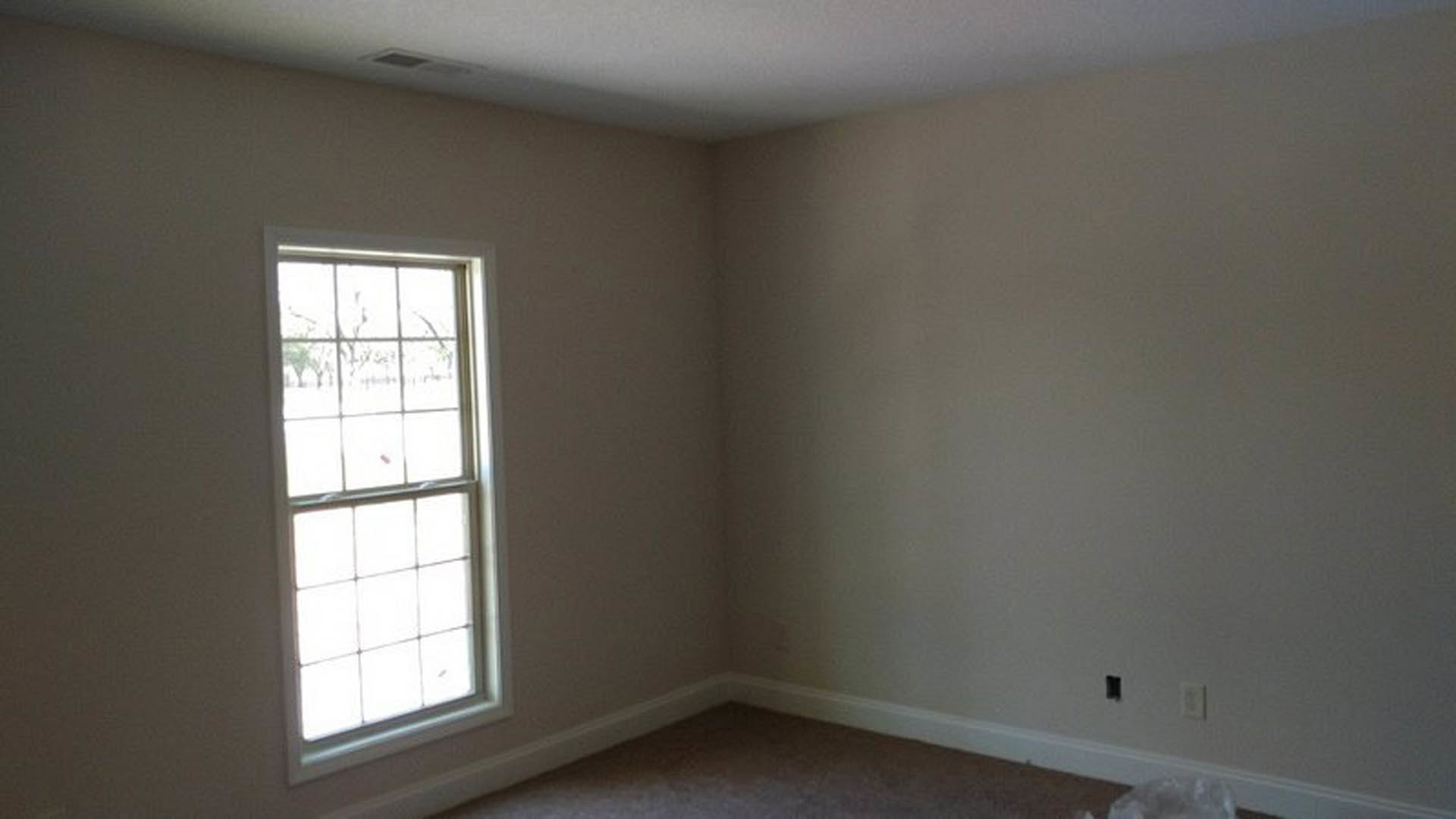 Bright room with white plaster walls, multi-pane window, light carpet flooring, and simple window blinds