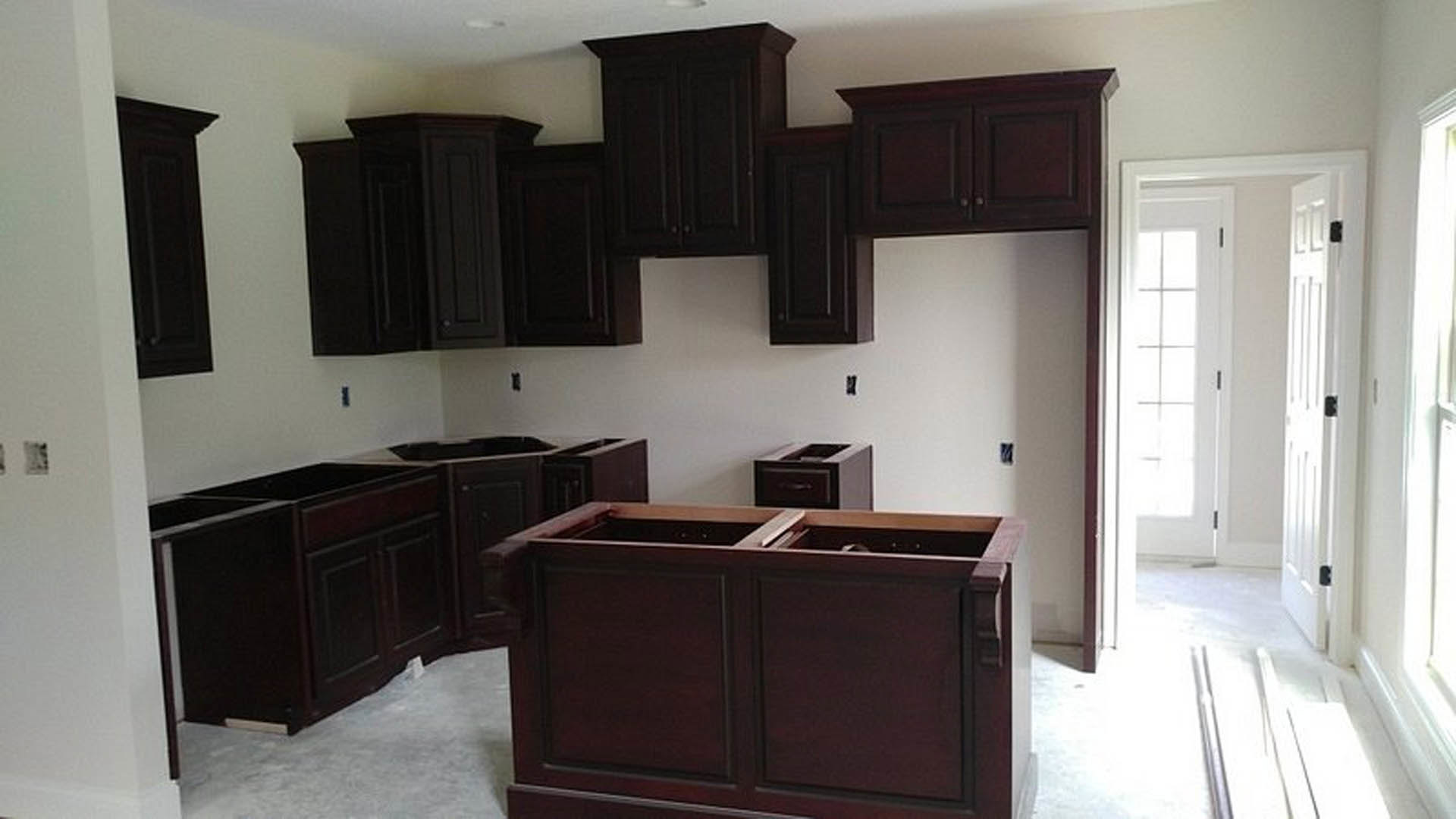 Kitchen featuring dark wood cabinets, white countertops, stainless steel sink, and a white door with glass window