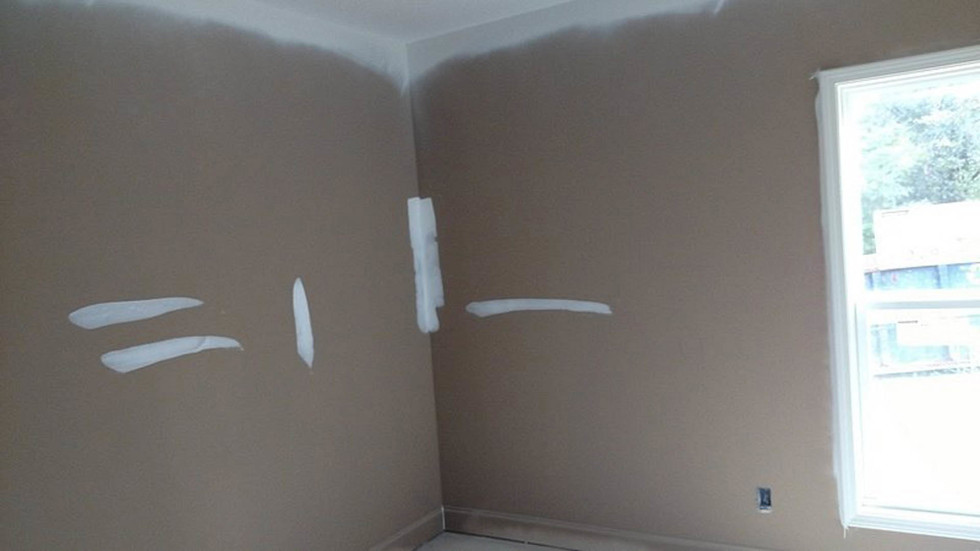 White-painted corner wall with white-framed window, brown surface featuring a white line, blurred figure and white object in foreground.