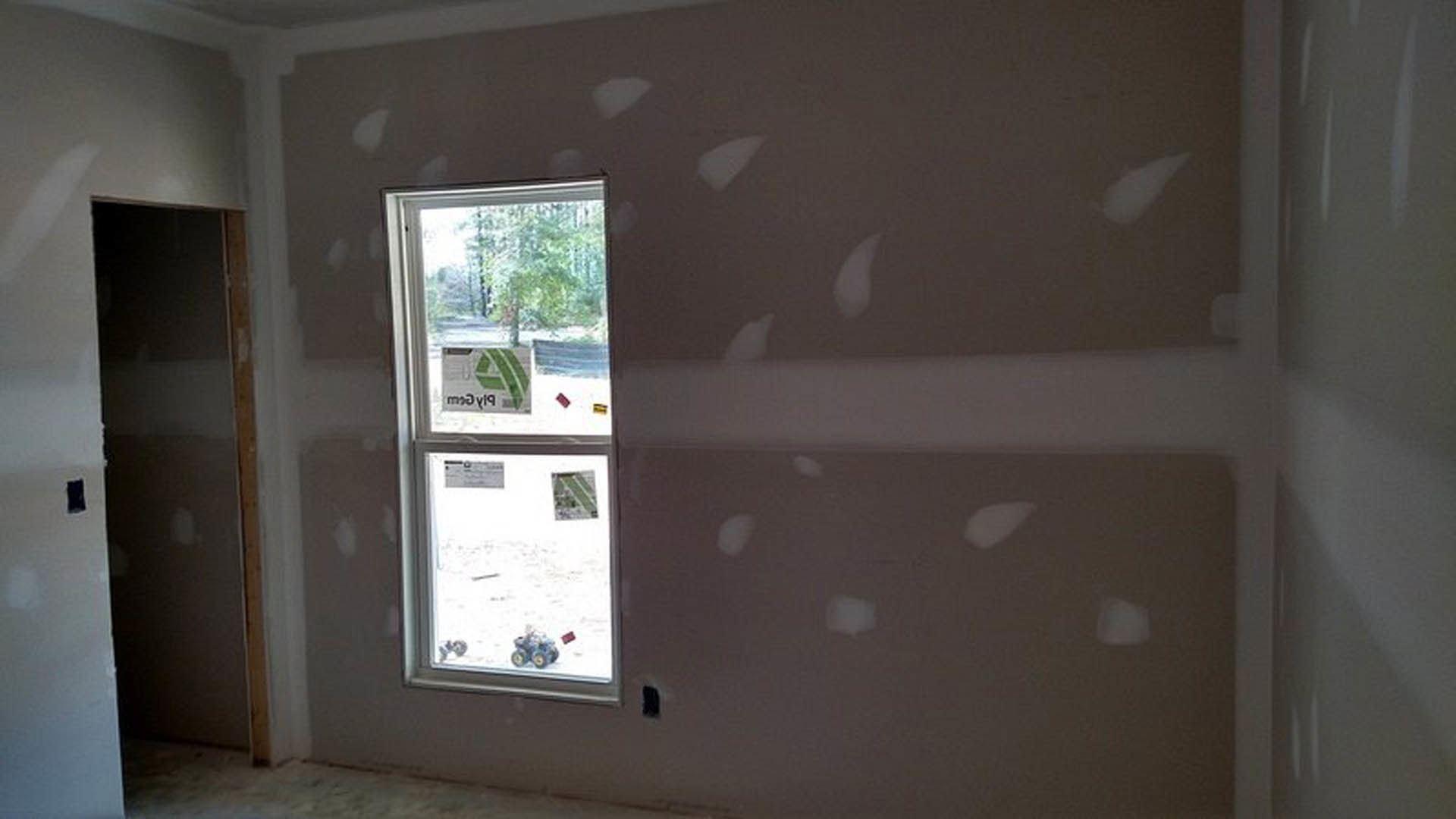 Large window set in a white-painted wall, natural light illuminating smooth plaster finishes and light-colored flooring in a modern residential interior.