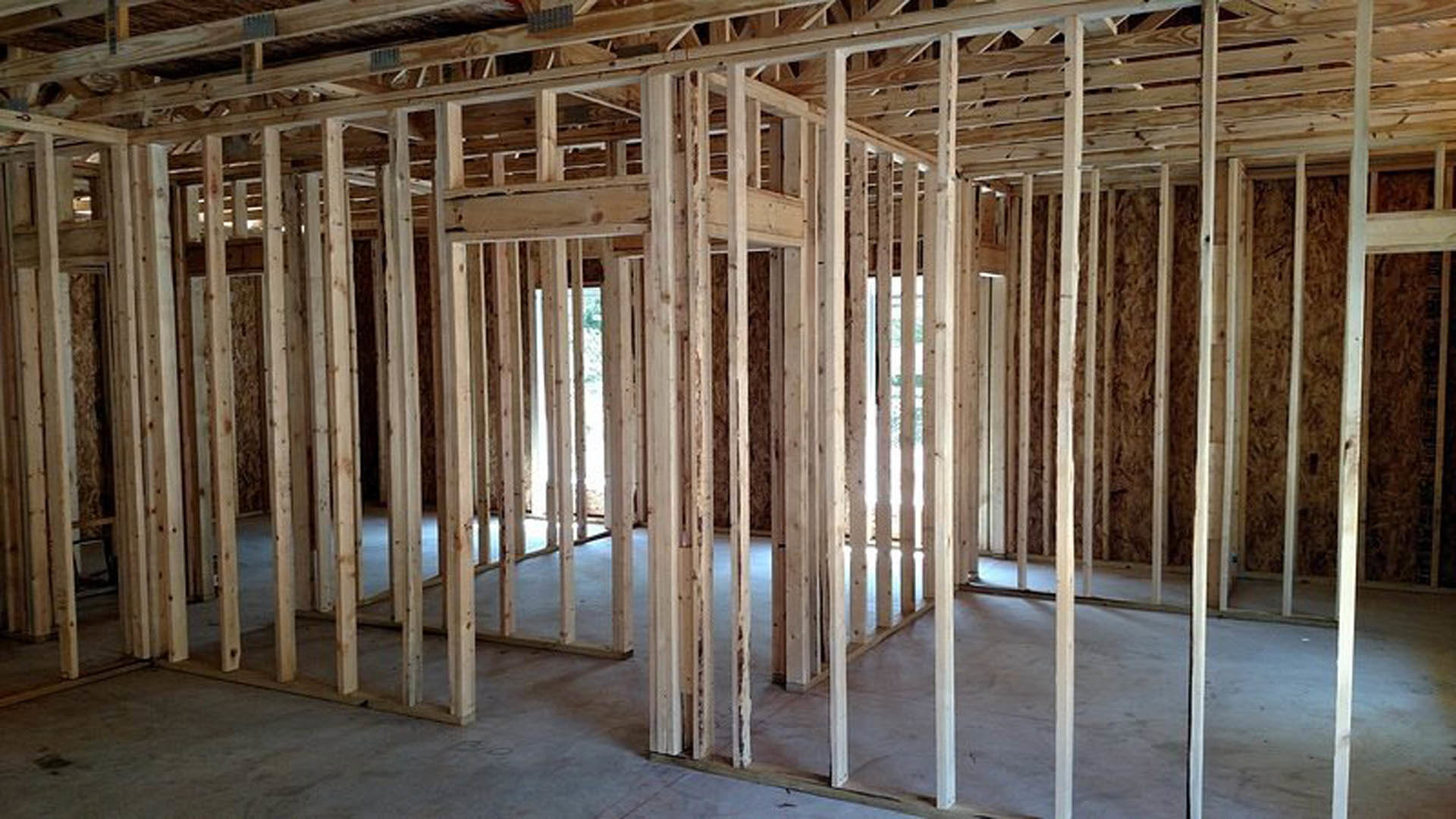 Unfinished room with exposed wood framing, ceiling beams, and lumber floor