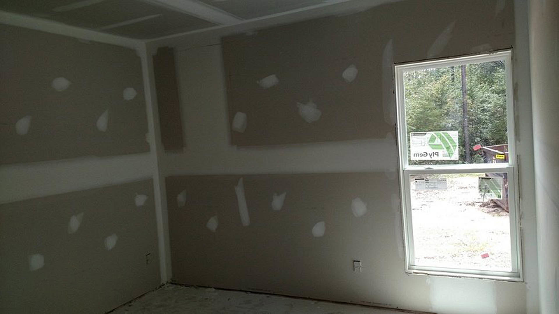 Bright room with smooth plaster walls, large window allowing daylight, minimal furnishings, and neutral finishes.