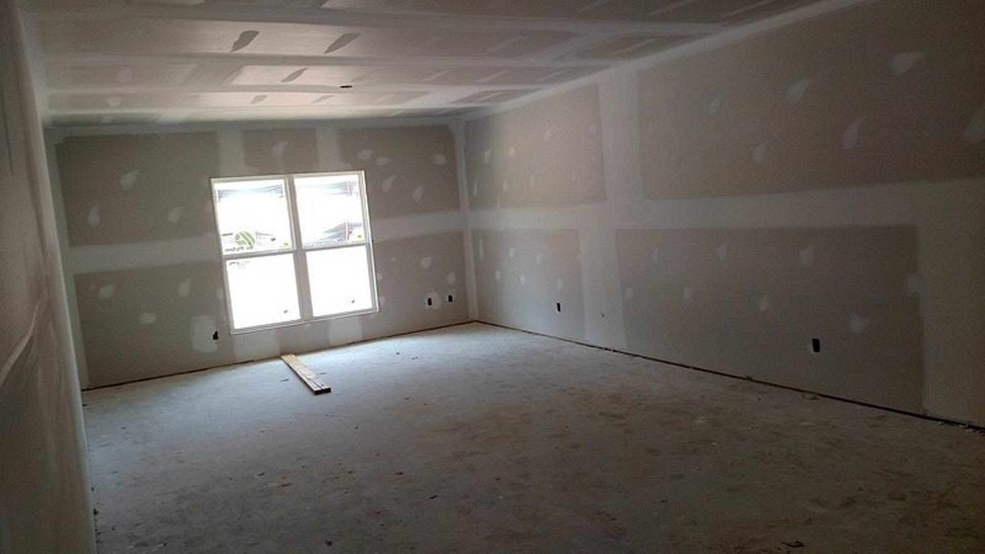 Sunlit room with plaster walls, wood plank flooring, large window, and ceiling fan.