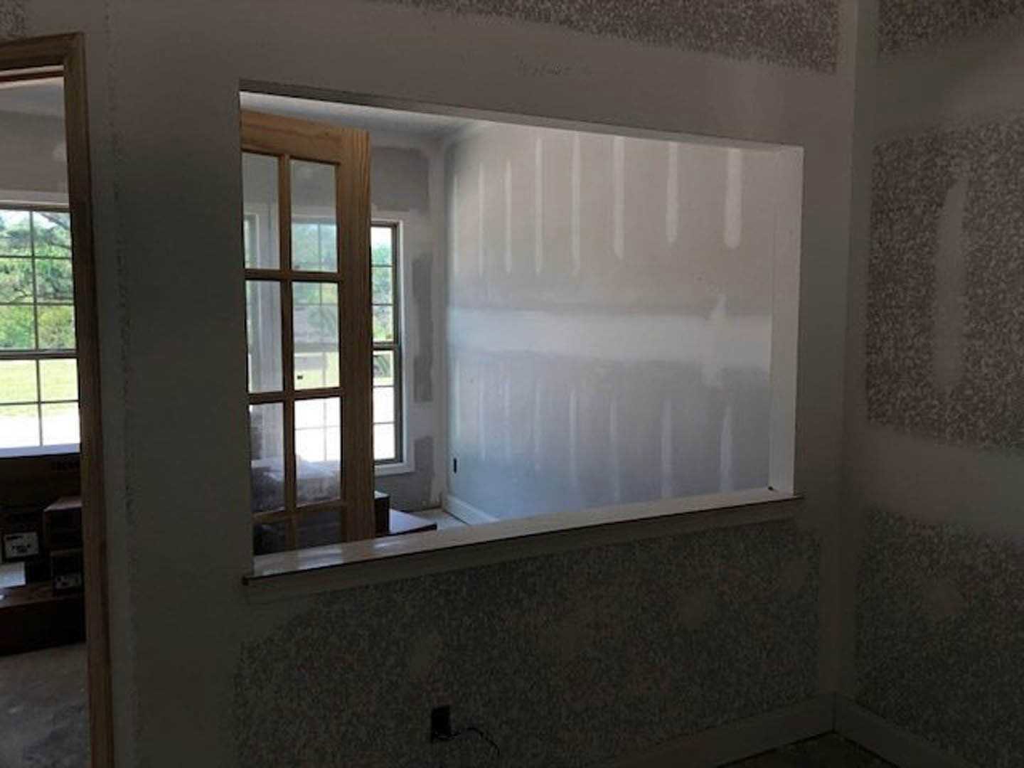 Bathroom with freestanding white bathtub beneath large window, white painted walls, gray door, and modern sink fixture