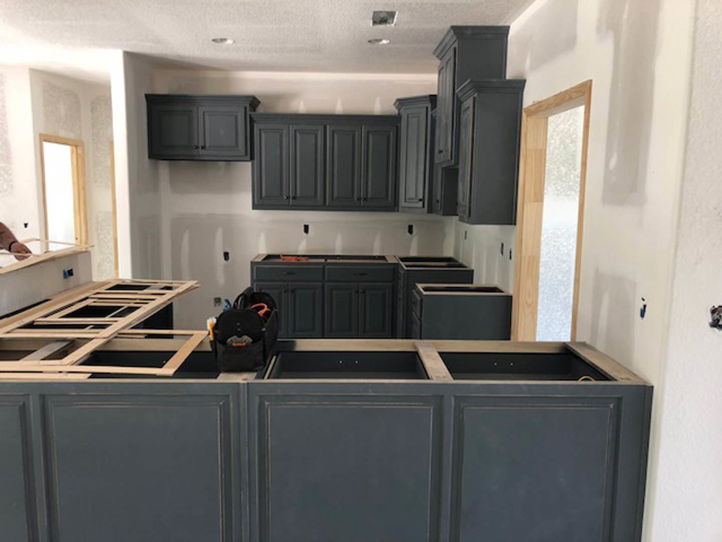Kitchen with matte dark wood cabinets, light stone countertops, stainless steel appliances, and neutral tile backsplash