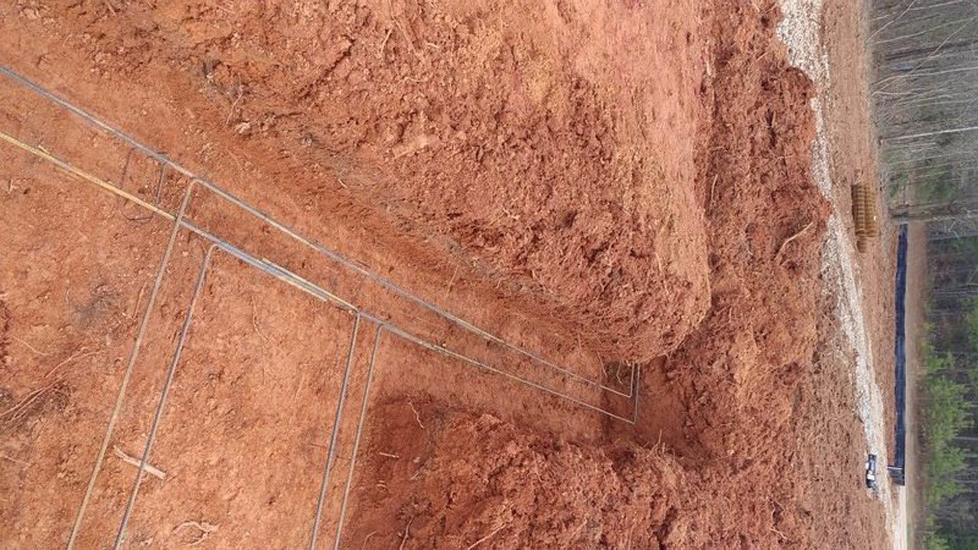 Dirt ground with exposed metal pipes, brown soil, and outdoor surroundings