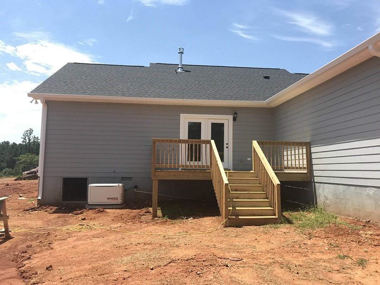 Two-story home with light siding, large windows, wooden deck, and exterior staircase leading to the porch