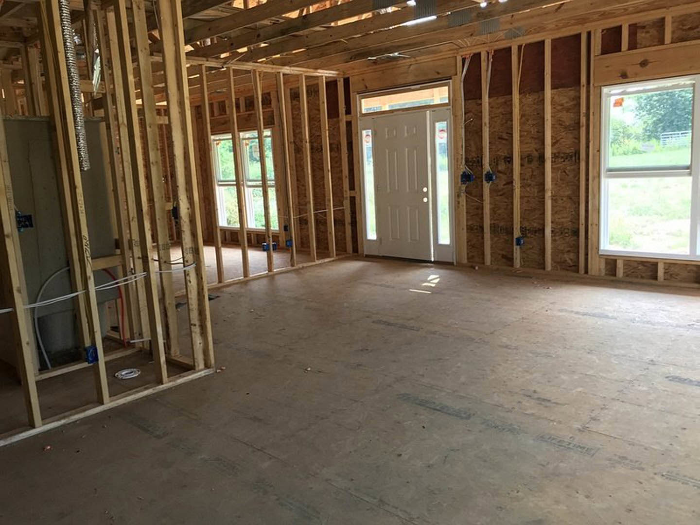 Bright room with wood plank ceiling, white door with glass panels, large window overlooking fenced yard, light-colored flooring