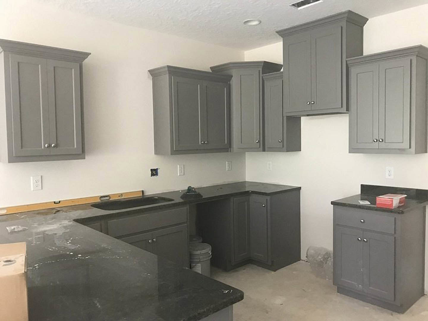 Grey shaker cabinets with matte black countertops, stainless steel sink, white tile backsplash, and modern kitchen appliances