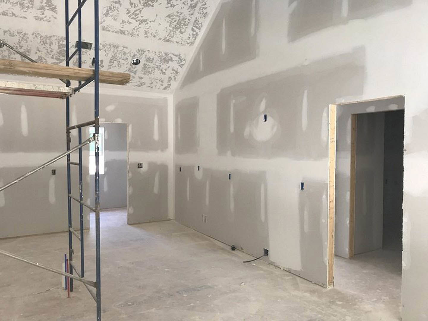 Open room with white plaster walls, exposed wooden beam, metal ladder, and smooth white floor