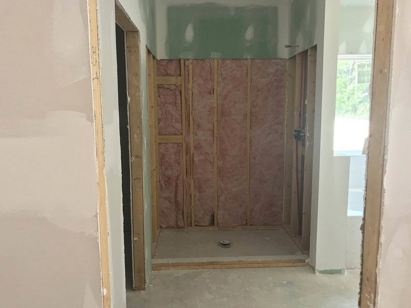 White plaster wall with brown wood trim, white floor, and wooden door in a residential interior.