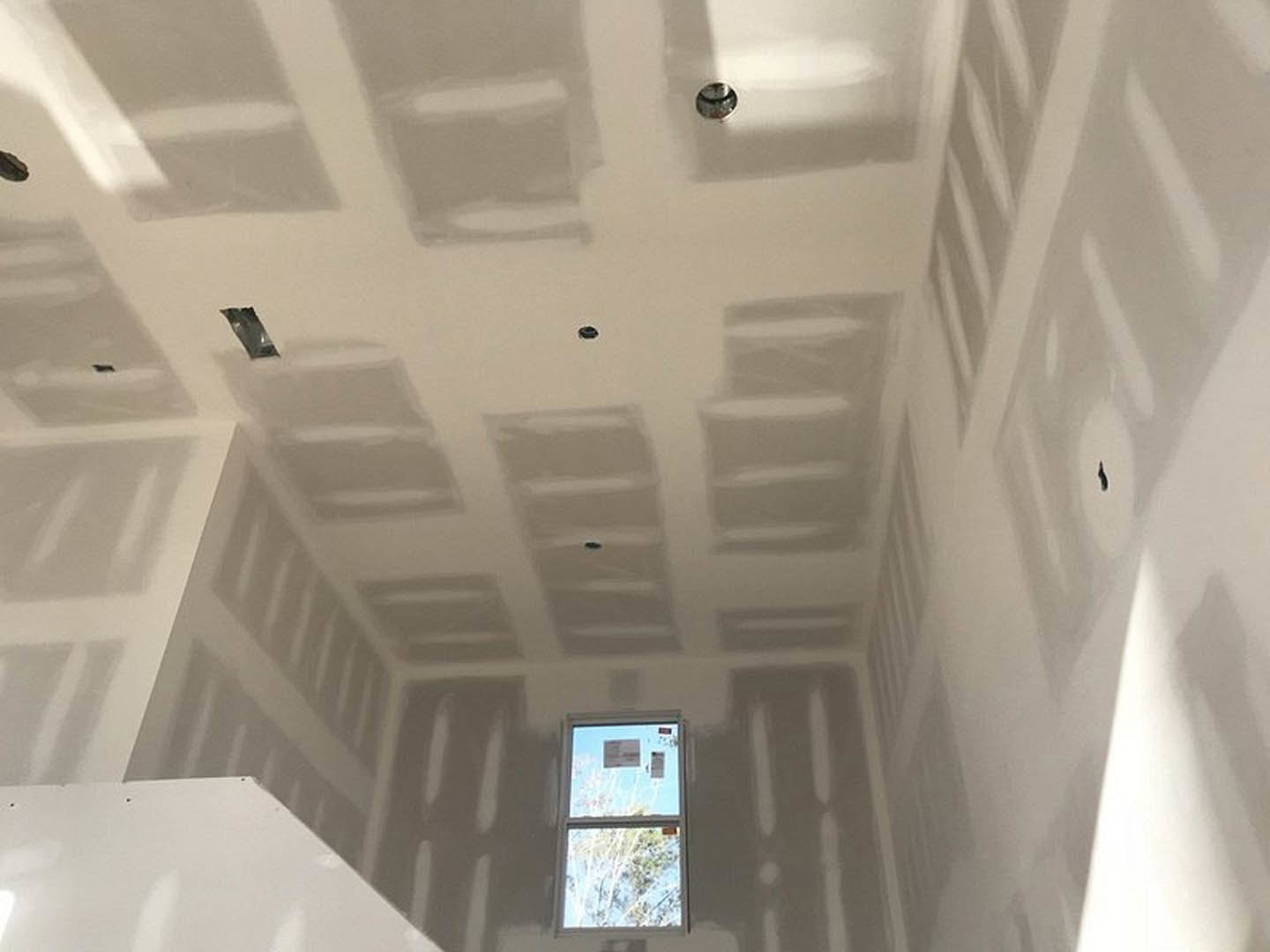 Bright room with two large windows, smooth white plaster walls, and ceiling, natural light highlighting minimalist finishes.