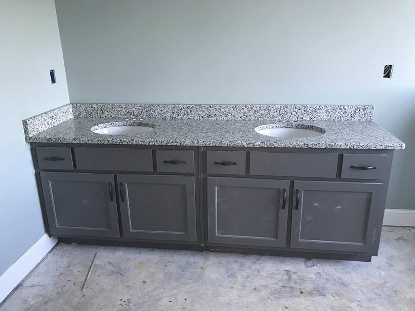 Bathroom with polished granite countertop, undermount sink, white tile backsplash, and dark wood cabinetry