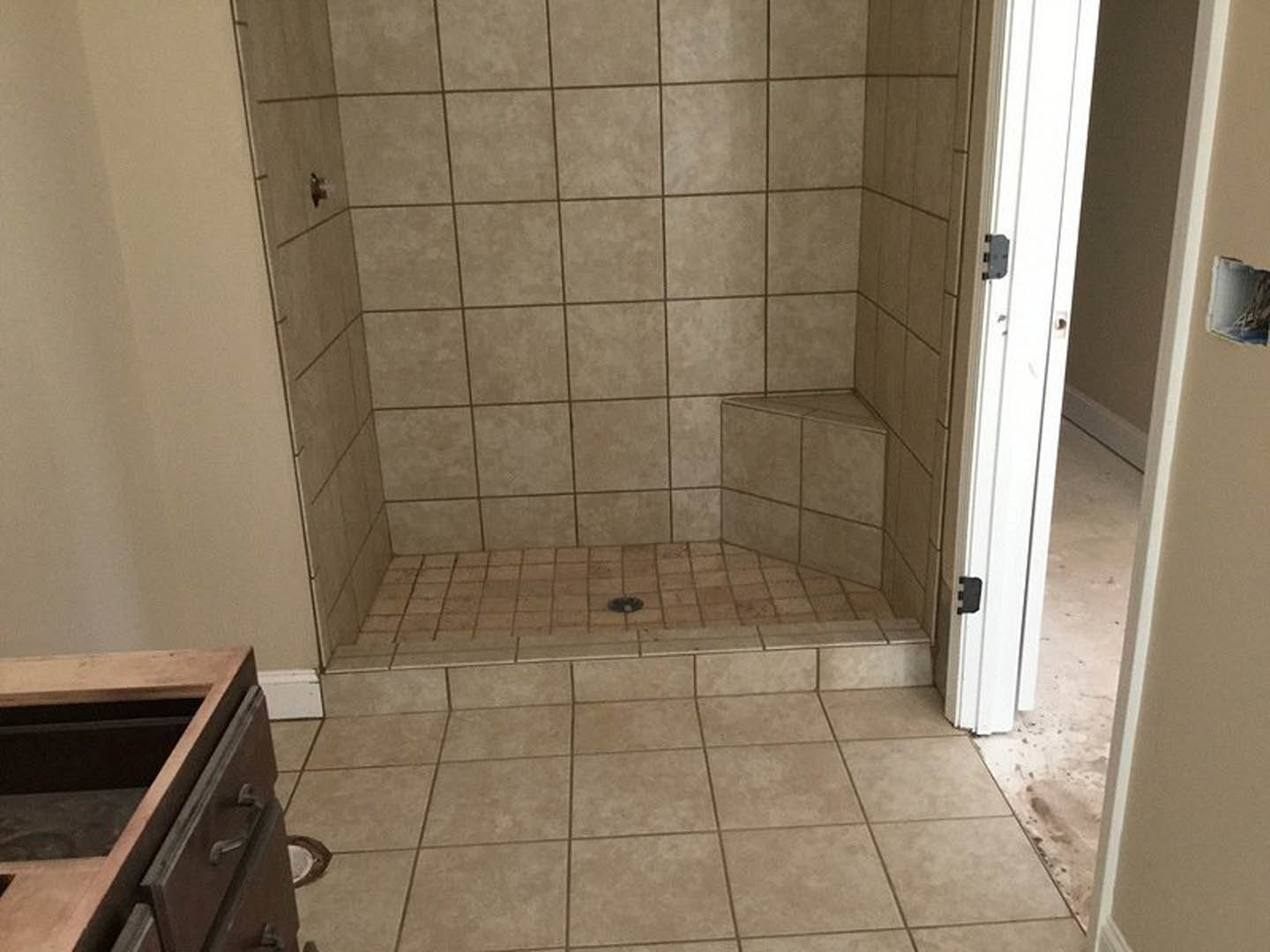 Walk-in shower with light gray tile walls, glass door, and chrome fixtures in a modern bathroom with tile flooring