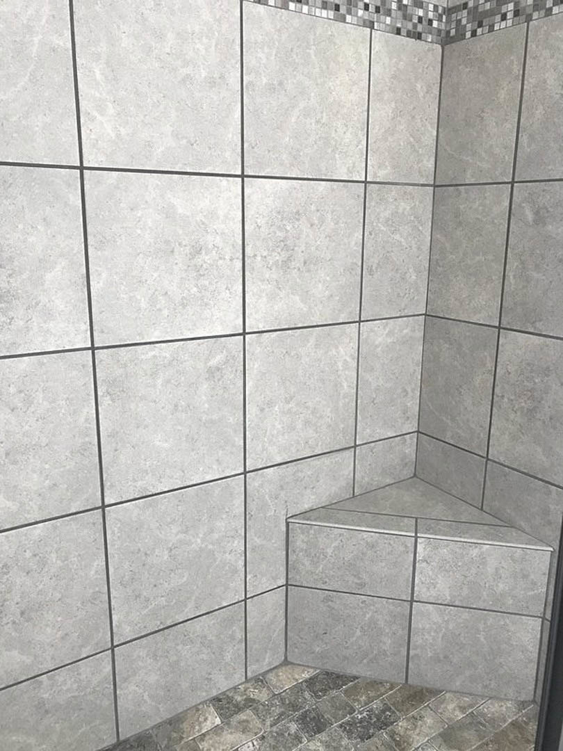 Grey tile wall meeting at a corner above stone tile flooring in a bathroom interior