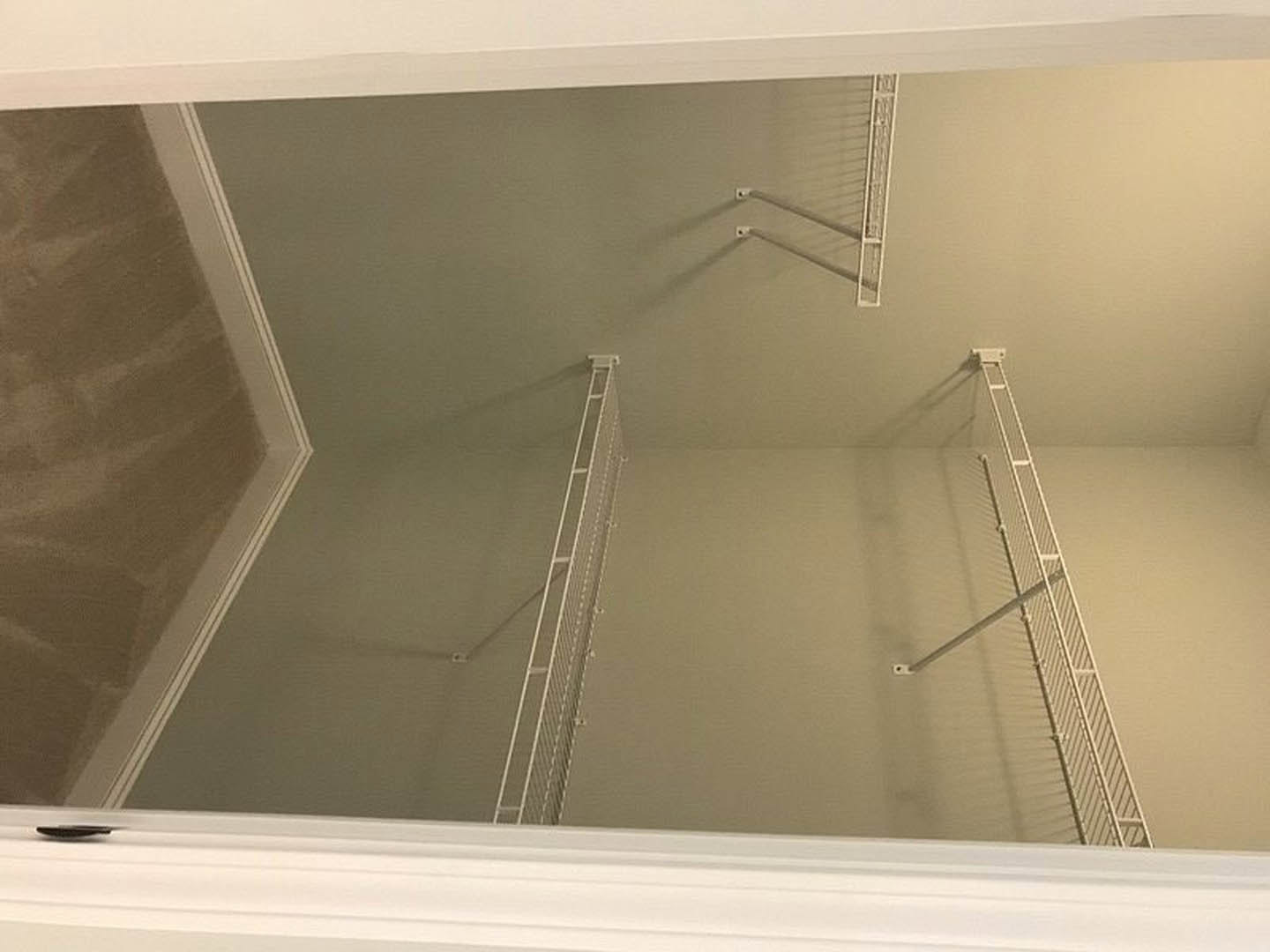 Corner closet with metal shelves, white plaster walls, and a white railing adjacent to a ladder mounted on the wall