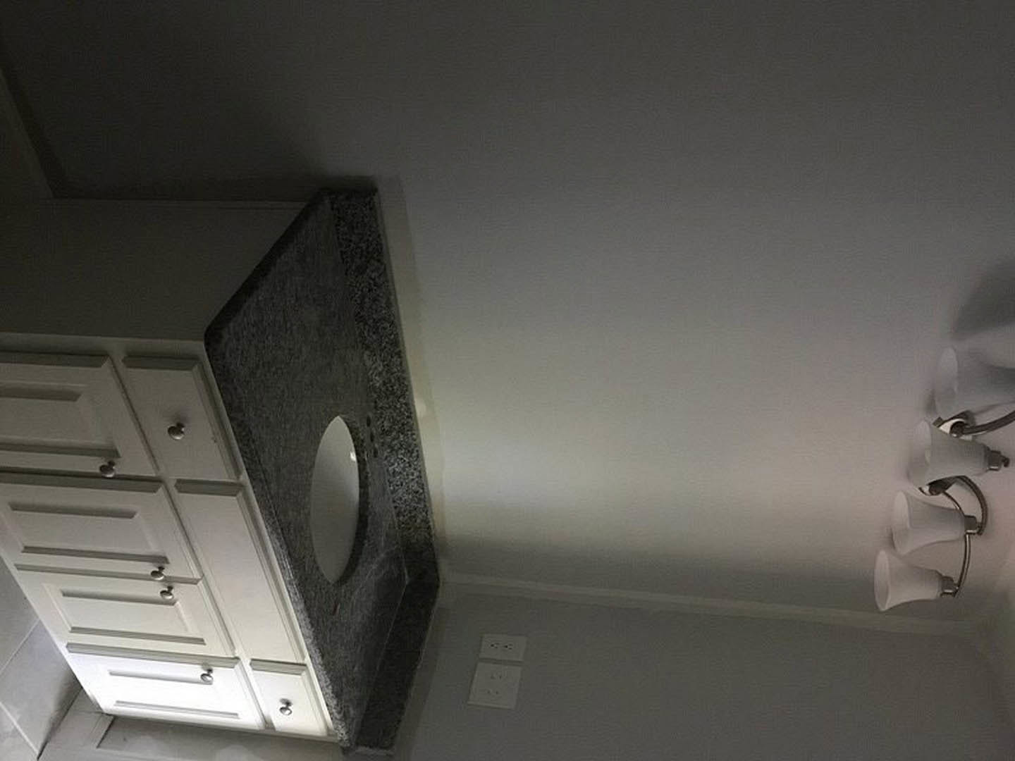 Bathroom with white walls, black accent stripe, modern sink, and dark wood cabinets
