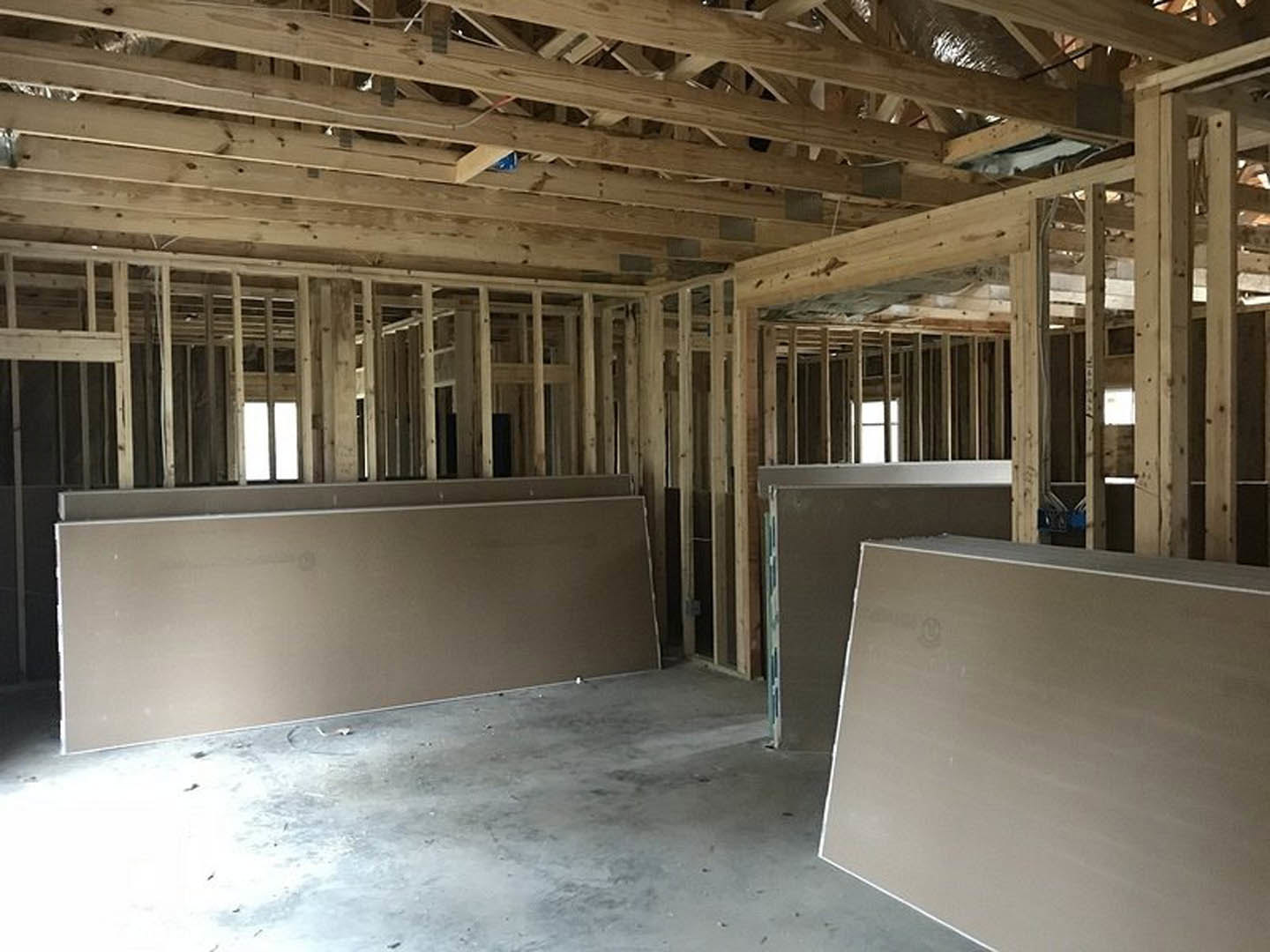 White-painted wall and ceiling with exposed wooden beams, two windows, and hardwood flooring in a modern residential room