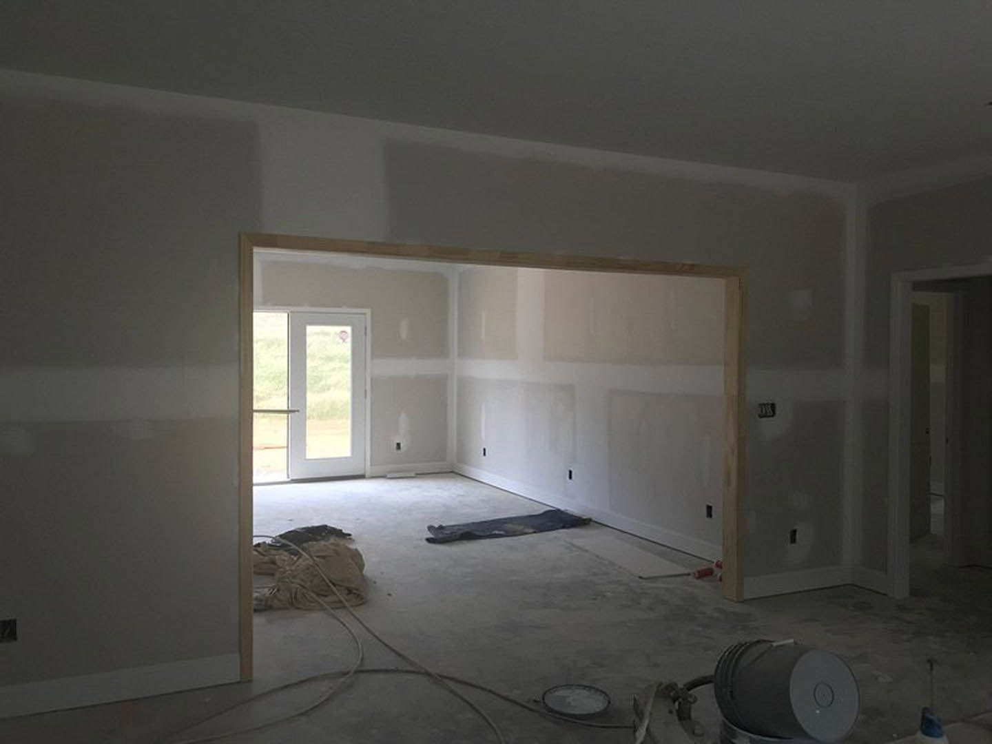 White-walled room with open door, light grey flooring, and scattered clothes near the entrance