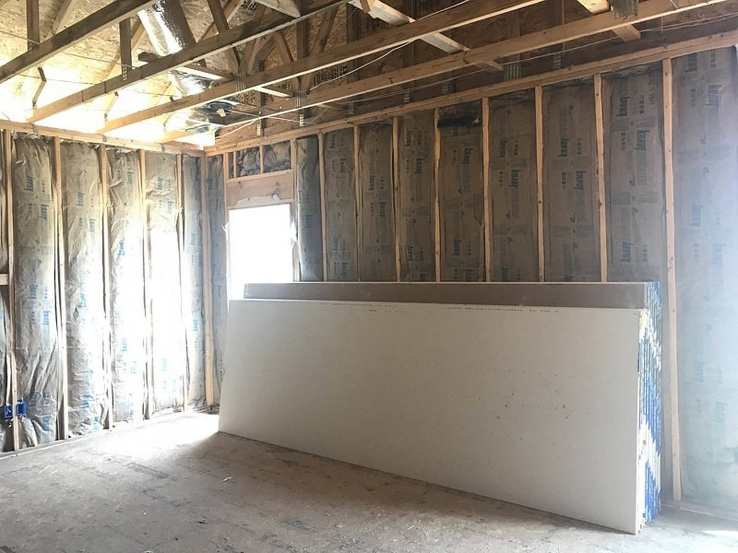 White plaster wall with exposed wooden ceiling beams, large window letting in natural light, indoor residential space