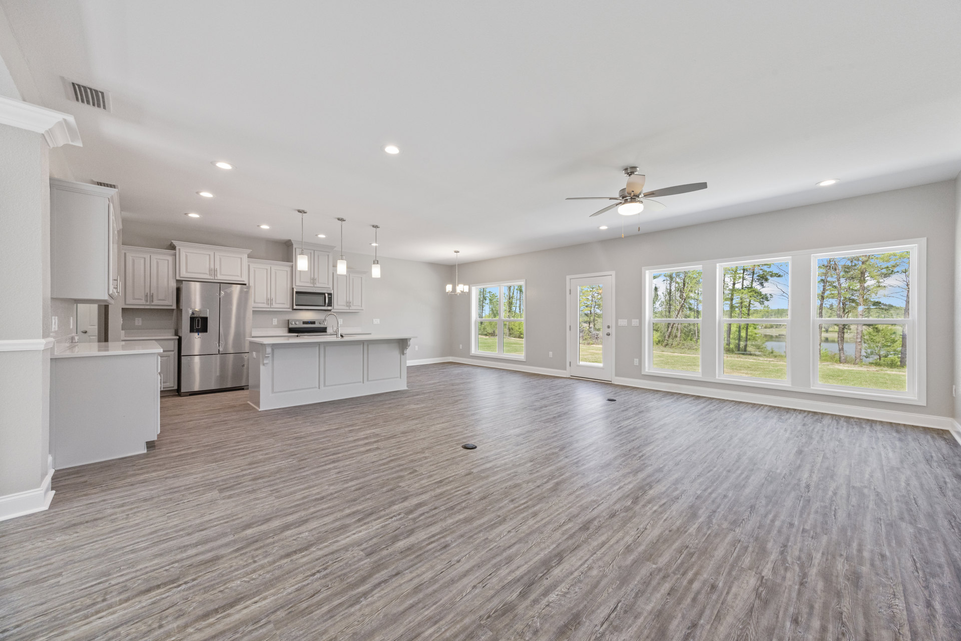 Spacious kitchen with white countertops, central island, wood flooring, large window, ceiling fan, and modern cabinetry
