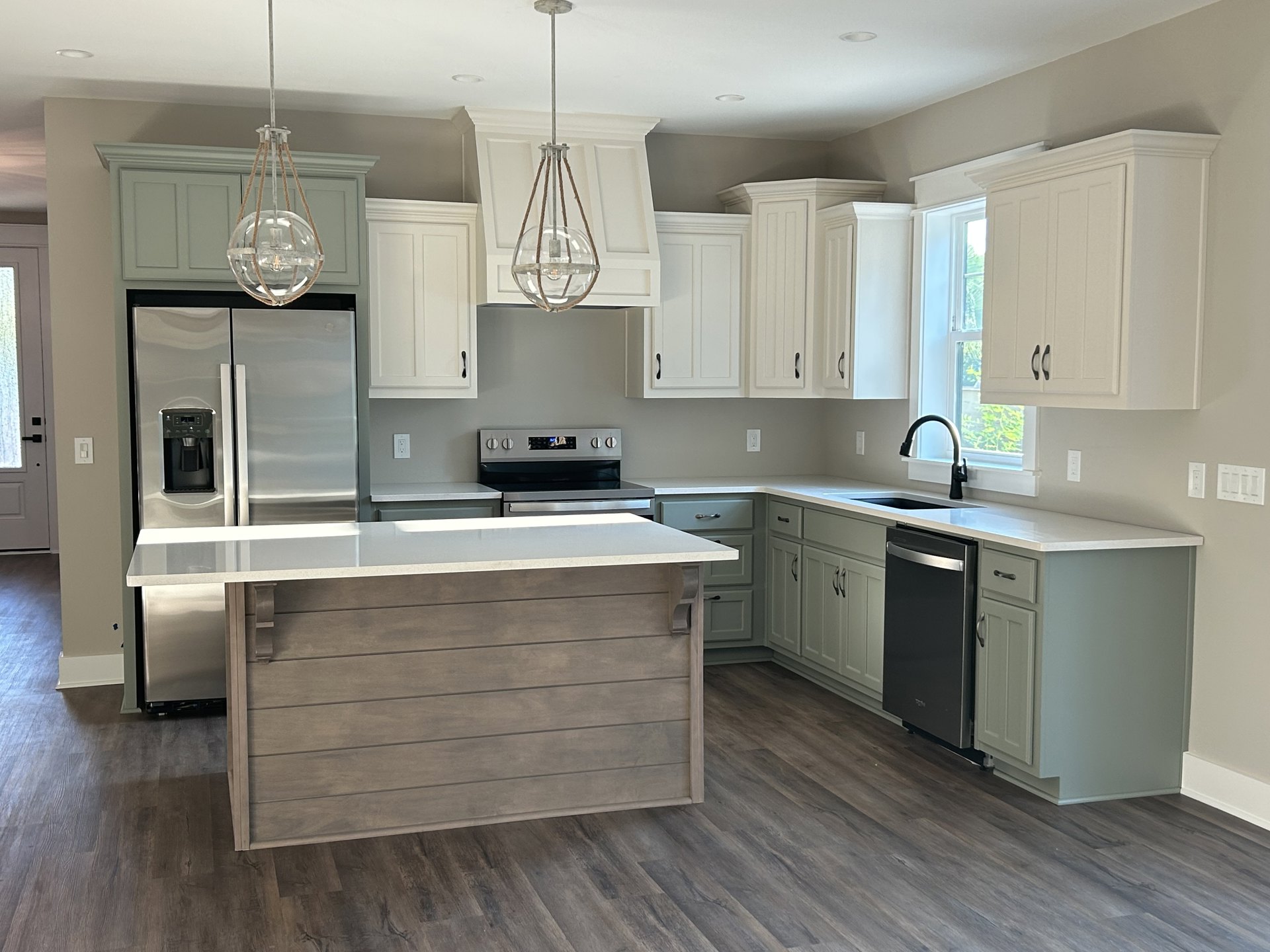White shaker cabinets, wood island with white quartz countertop, stainless steel refrigerator, pendant lighting, tile backsplash, hardwood flooring, undermount sink, brushed nickel