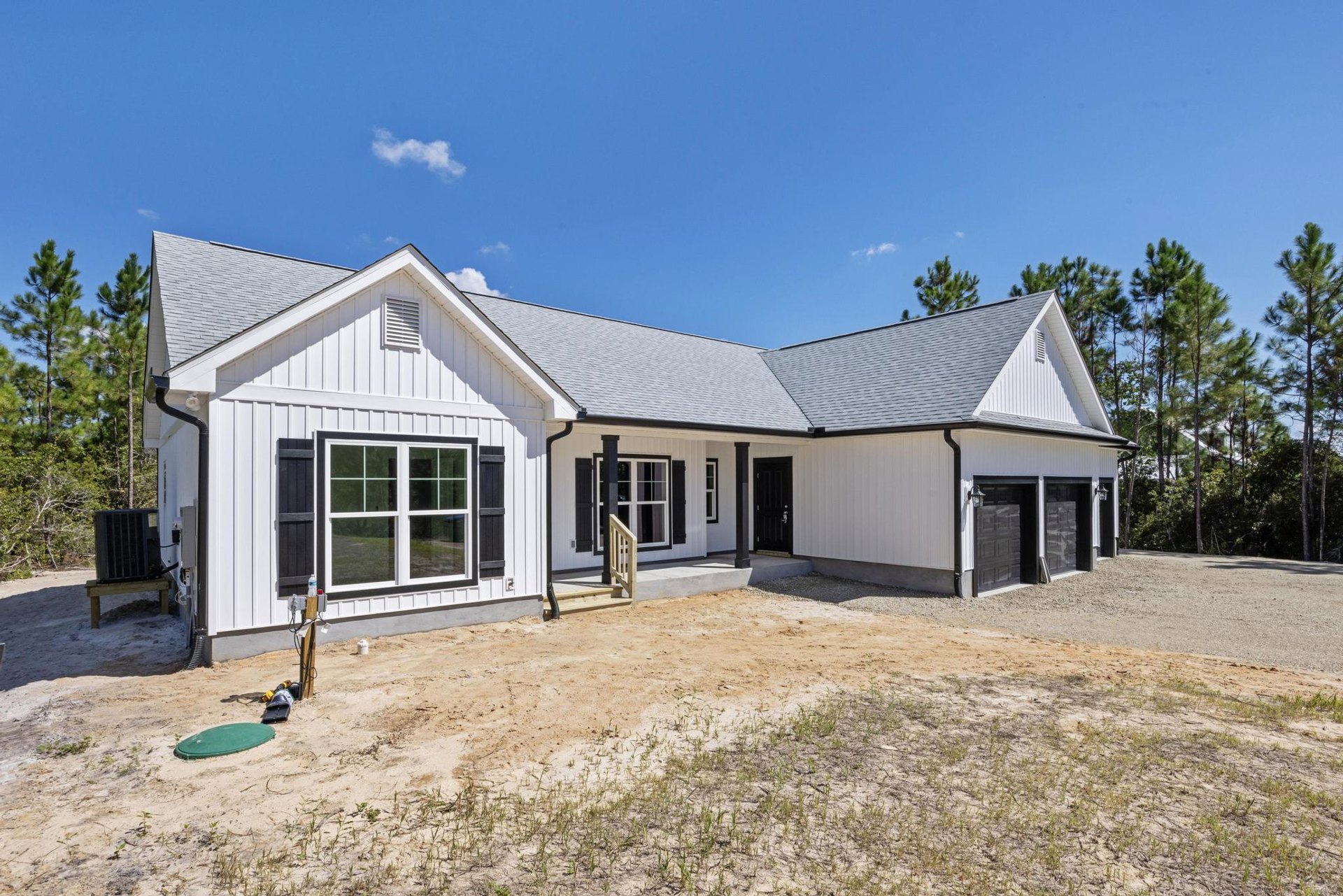 White house with black trim, dirt yard in front, green object on ground, close-up views of window and vent, cloudy sky overhead