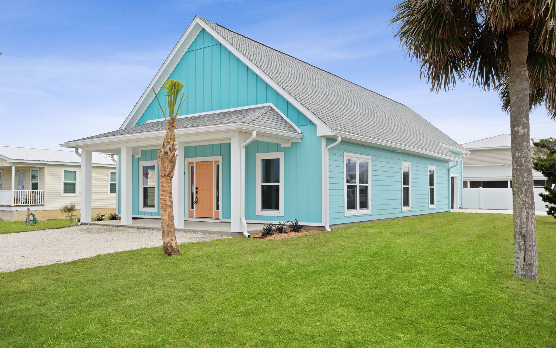 Blue siding house with white trim, palm tree in front yard, manicured lawn, porch, and Jesse James Home Museum visible in background.